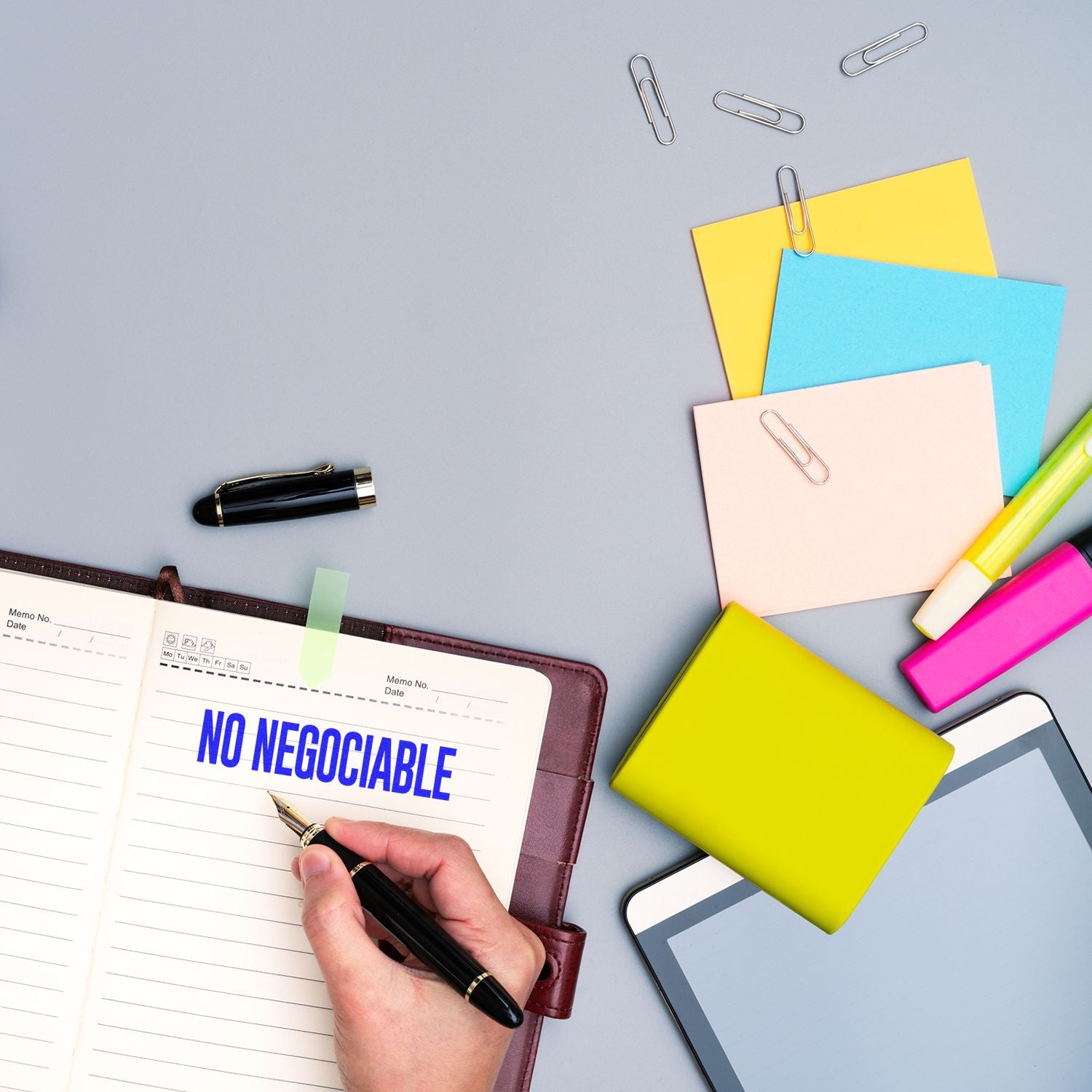 Man writes No negociable on planner with pen; office desk with sticky notes, paper clips, and stationery for goal setting.