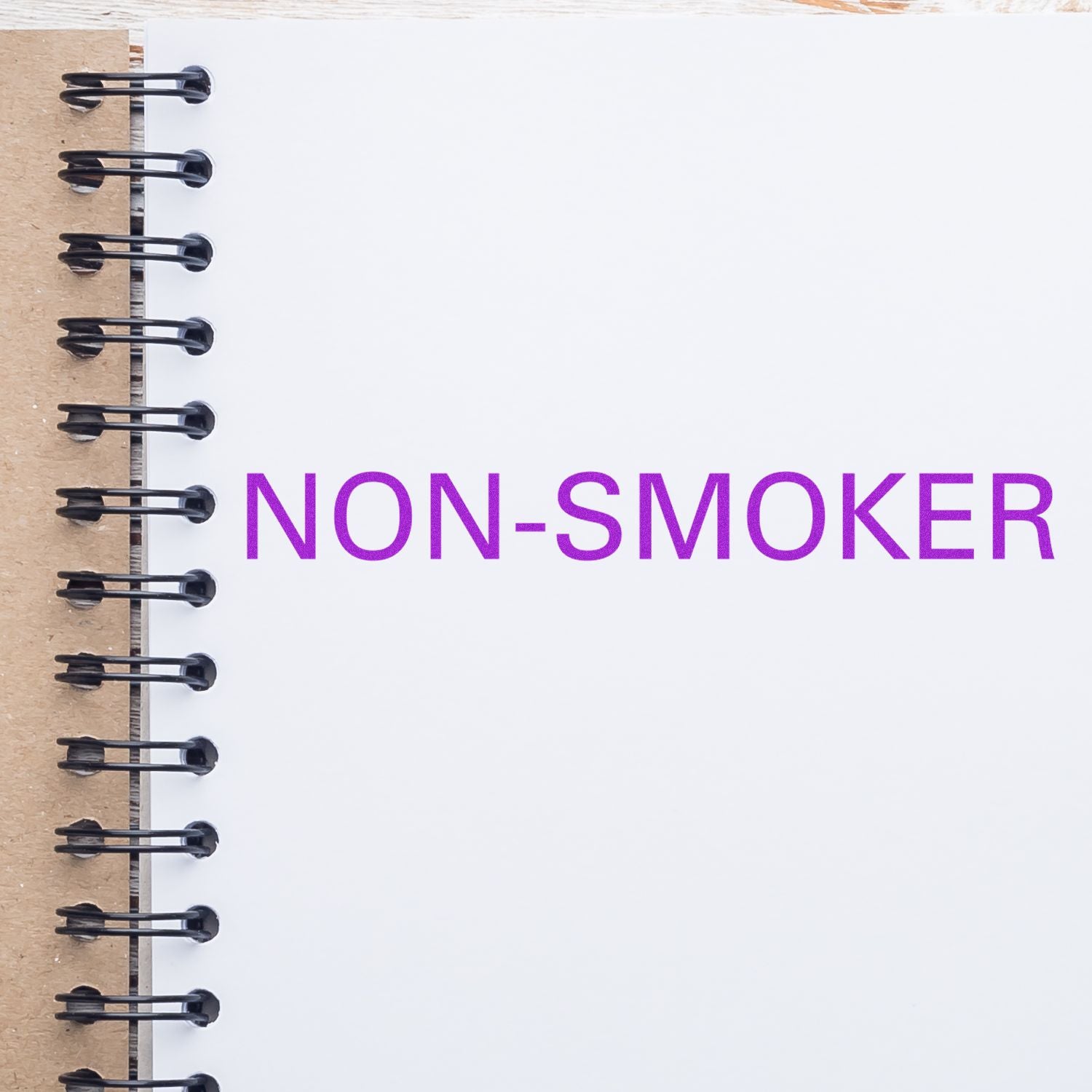 Non-smoker notice on a spiral notebook page with bold purple text NON-SMOKER, showing a smoking-free policy.