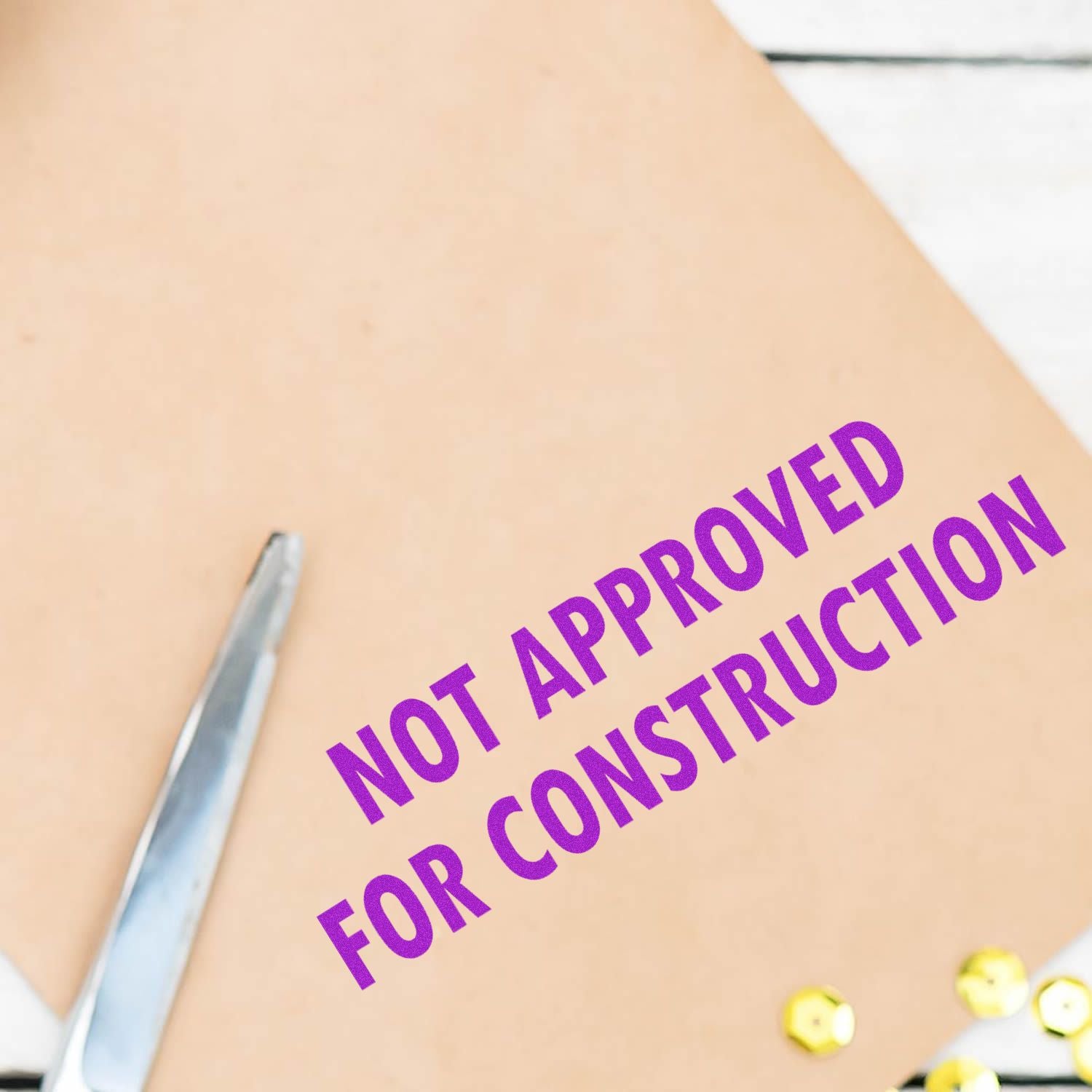 Close-up of a construction plan showing Not Approved for Construction text on a document with safety pins.
