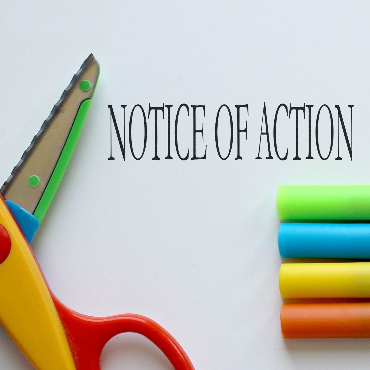 Colorful scissors and markers beside a Notice of Action document on a white background, symbolizing office paperwork and legal notification.