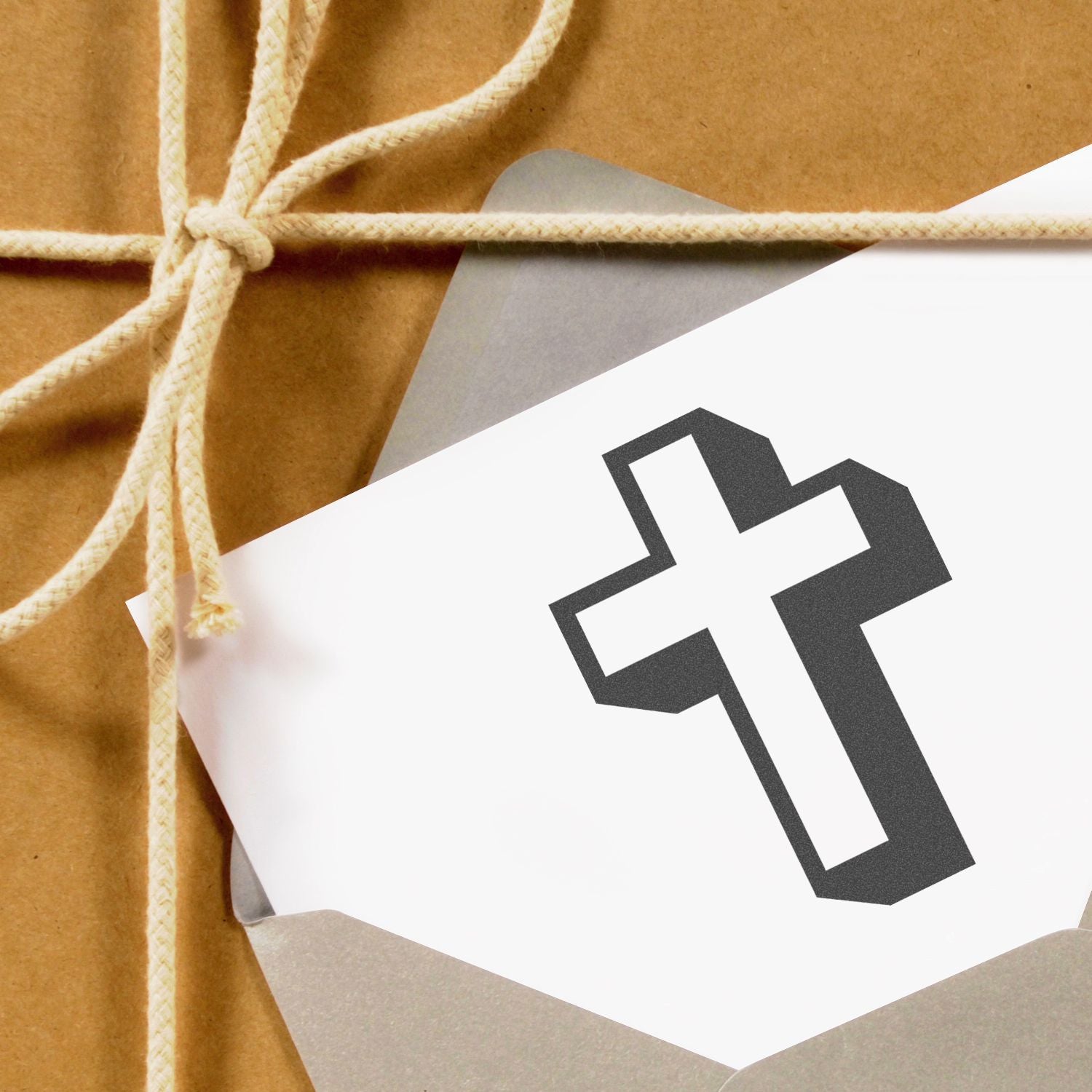 Wrapped gift package in kraft paper tied with twine, featuring a black cross symbol on a white tag.