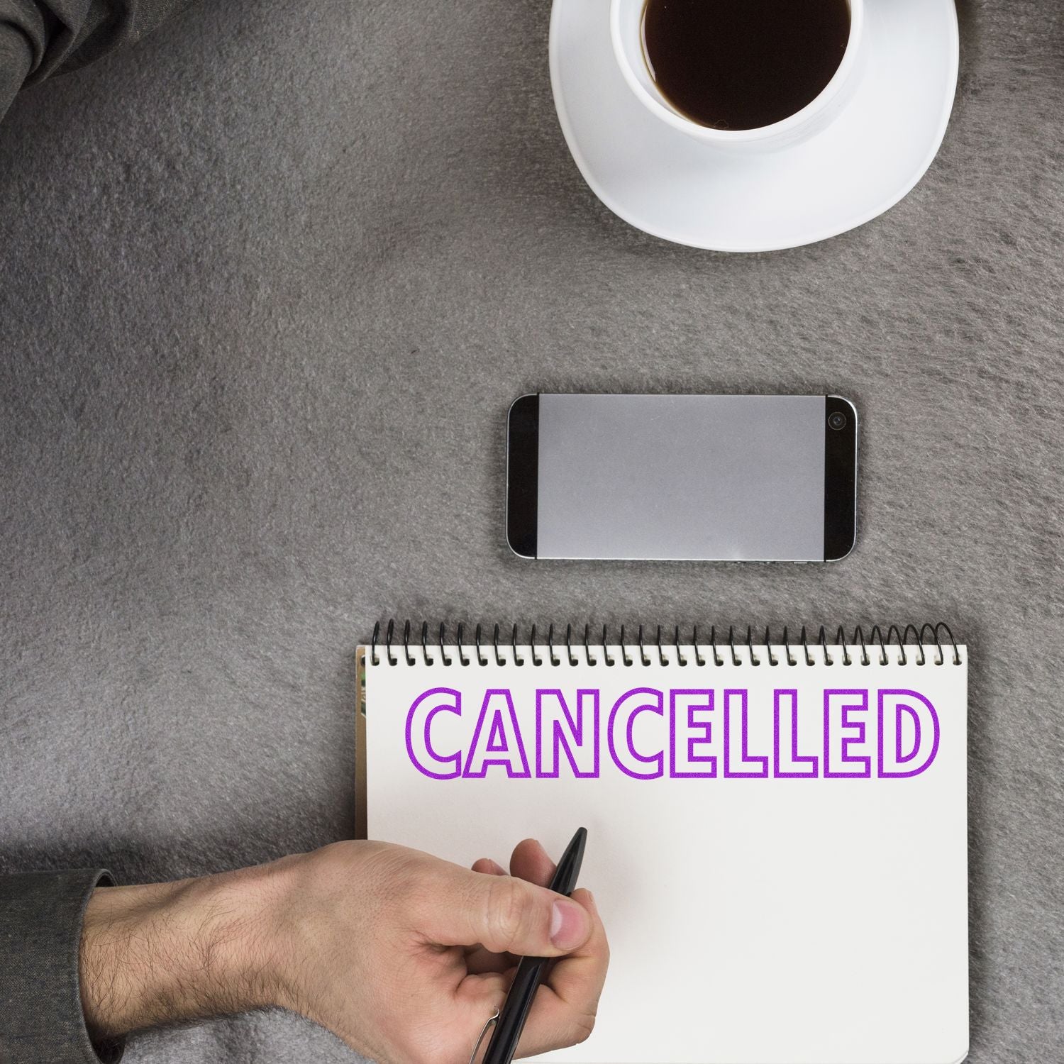 Desk planning scene with notebook reading CANCELLED and pen, symbolizing cancelled plans and updates.
