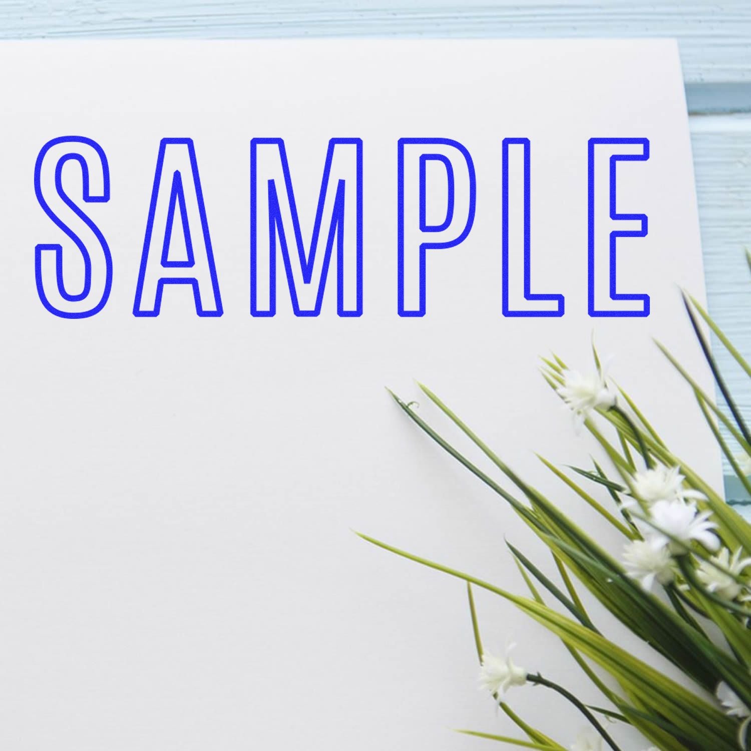 Sample stationery design with blue SAMPLE lettering and white flowers for spring branding