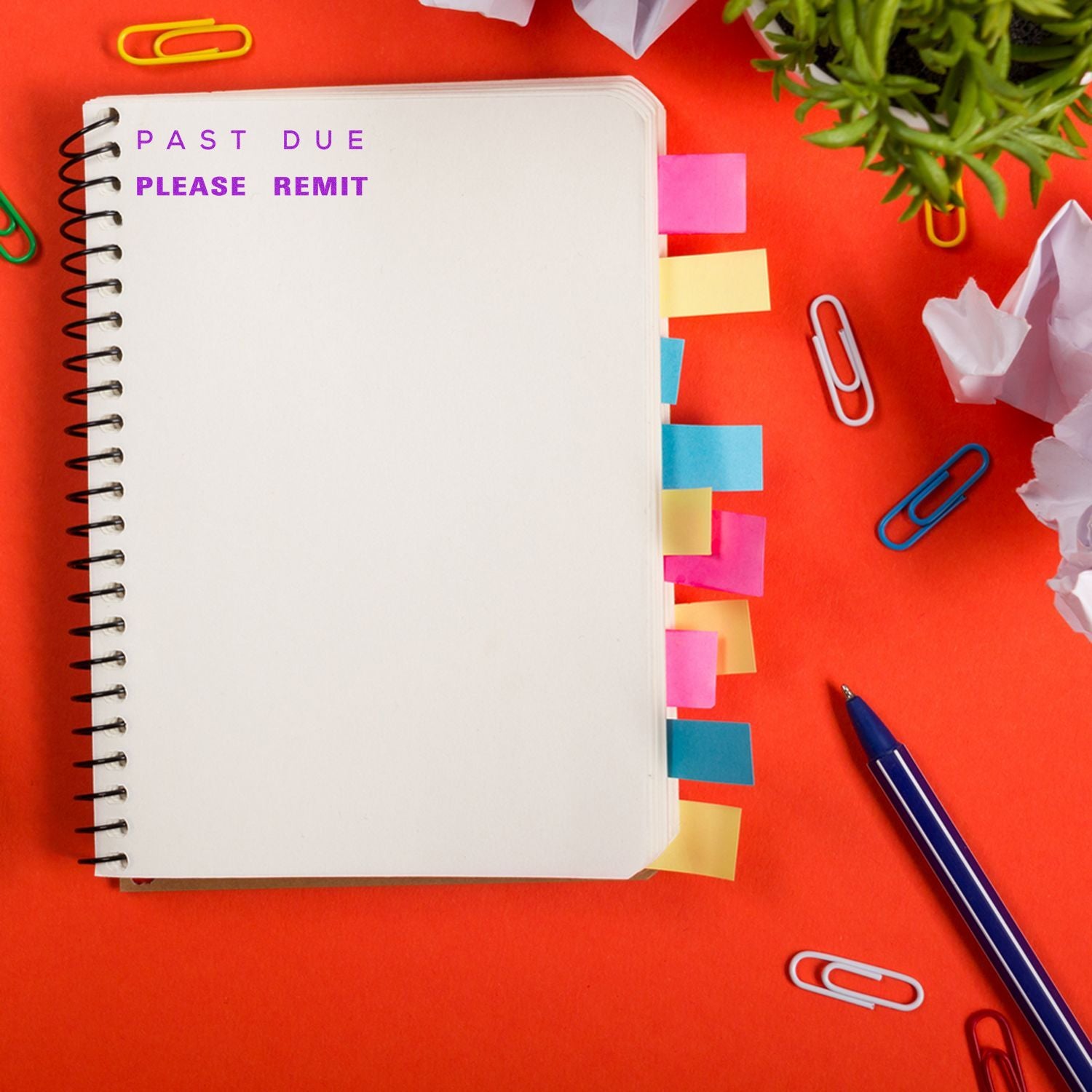 Past due please remit notebook on a red desk with colorful sticky tabs, paper clips, pen, and plant, concept for overdue payment reminder.