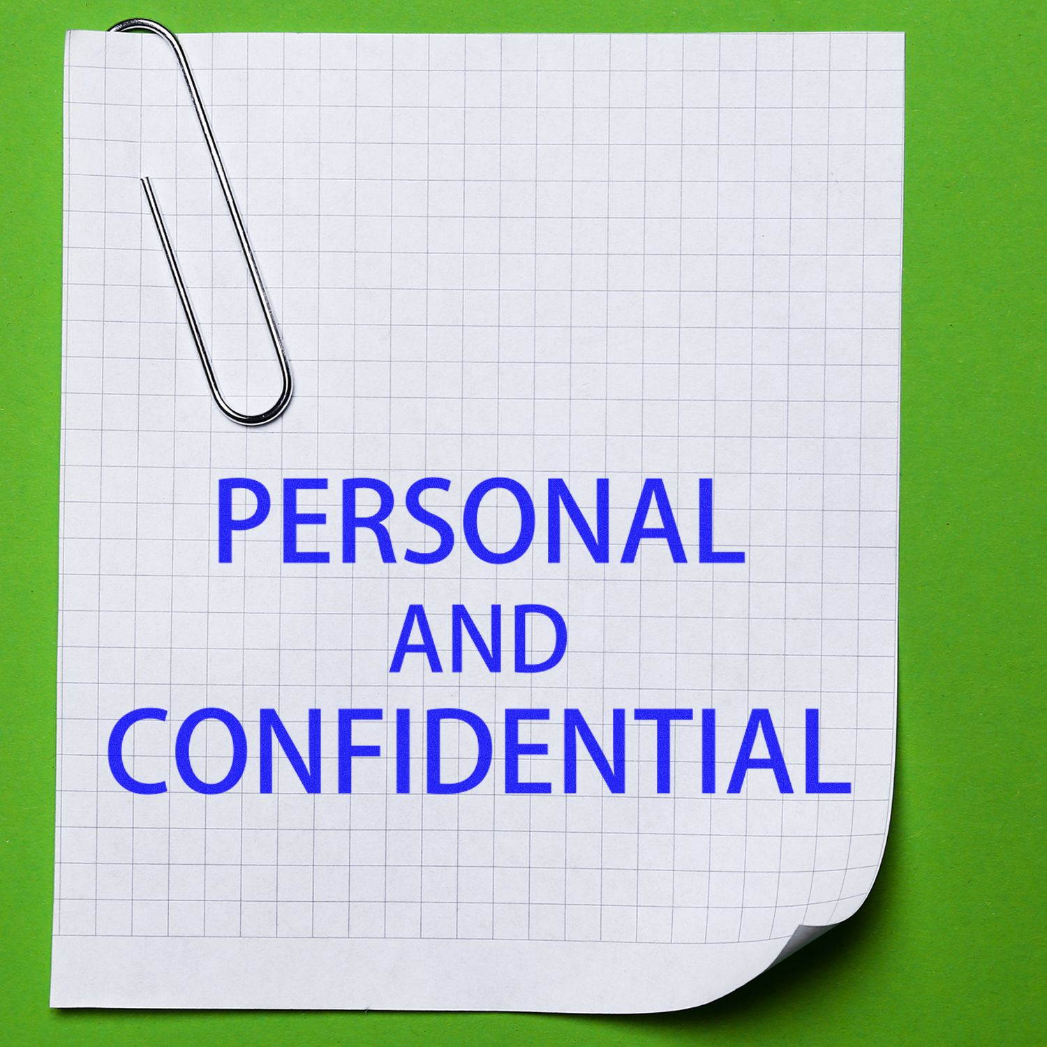 Paper clipped note with Personal and Confidential text on graph paper background, privacy and document security concept.
