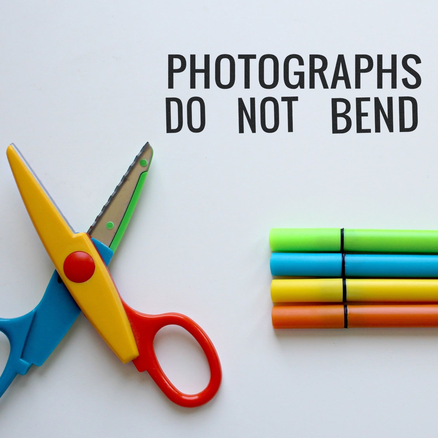 Photographs do not bendscissors and colored markers on white background, emphasizing photo protection and framing guidelines.