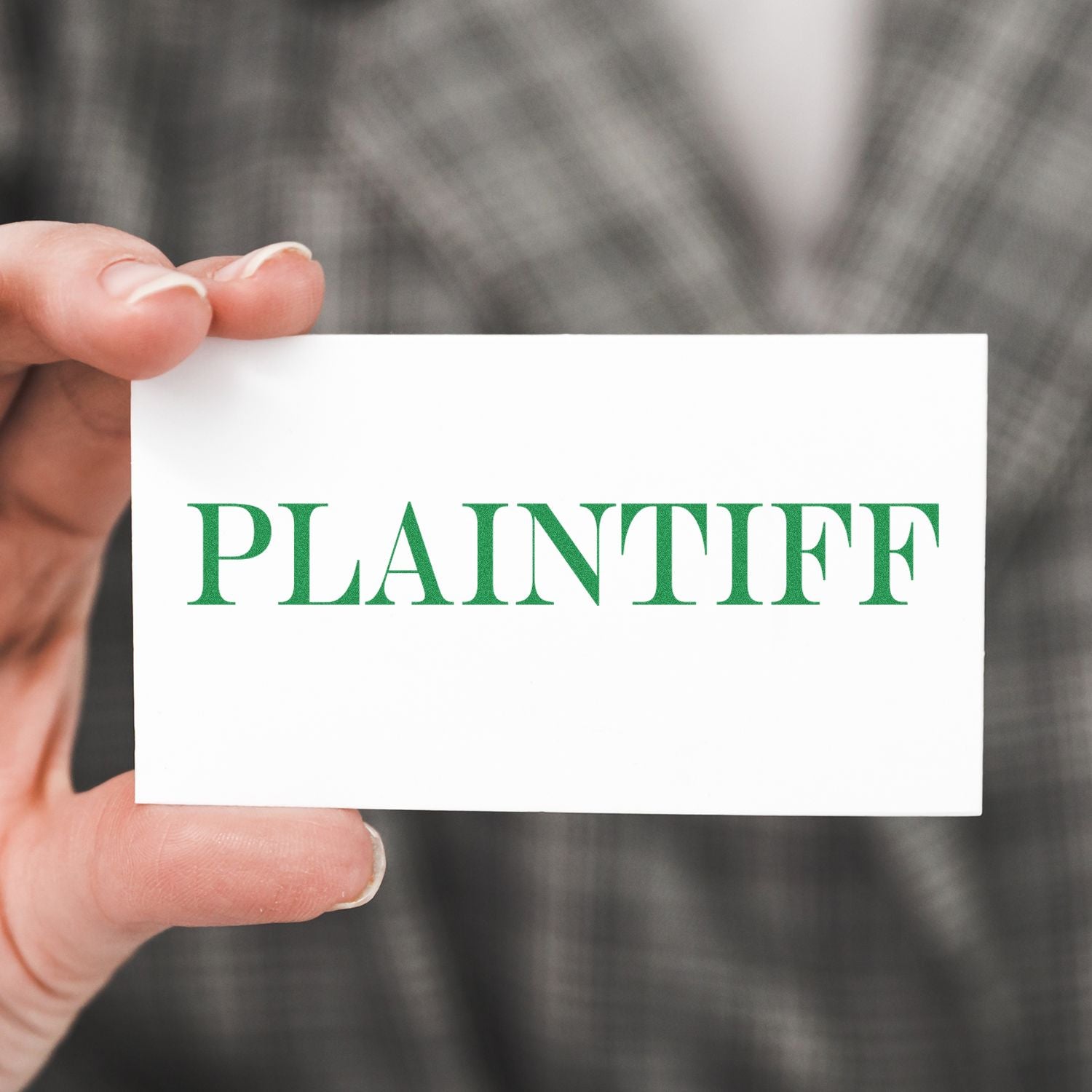 Hand holding a white card reading PLAINTIFF, symbolizing legal case documents and court filings.
