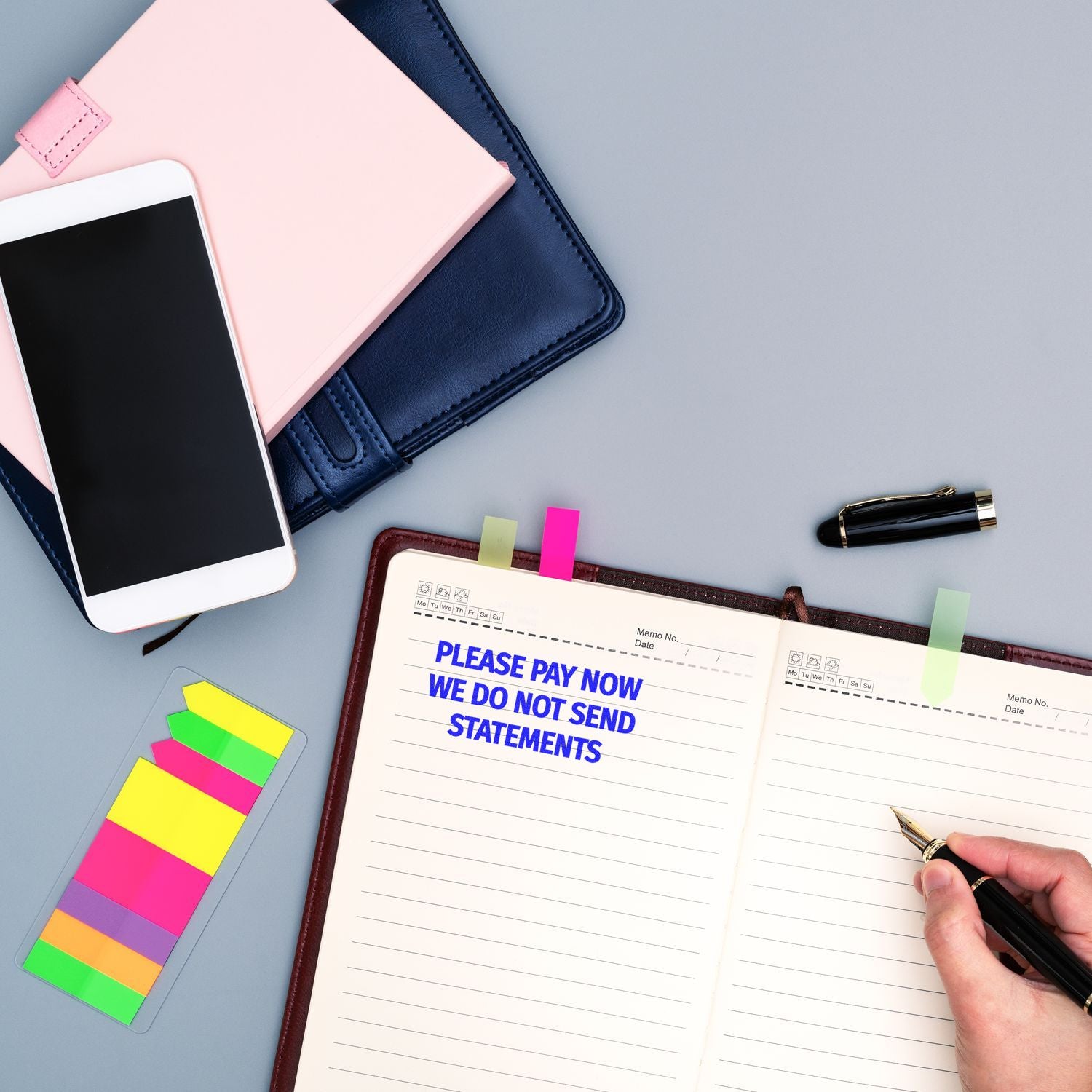 Personal finance planner with smartphone, notebook, colorful sticky tabs, and pen for budgeting and bill payment organization.