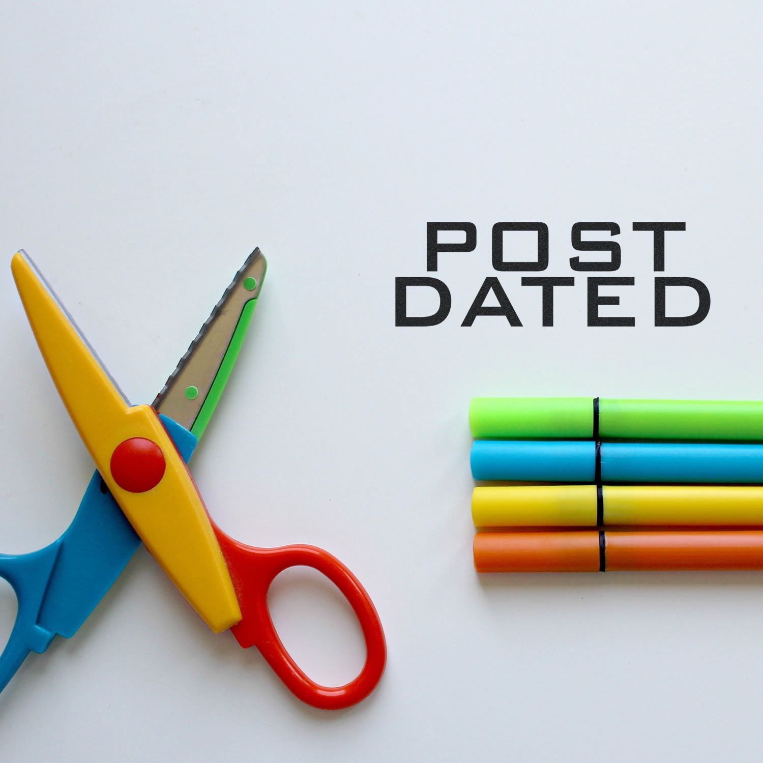 Colorful scissors and markers beside the words Post Dated on a white background.