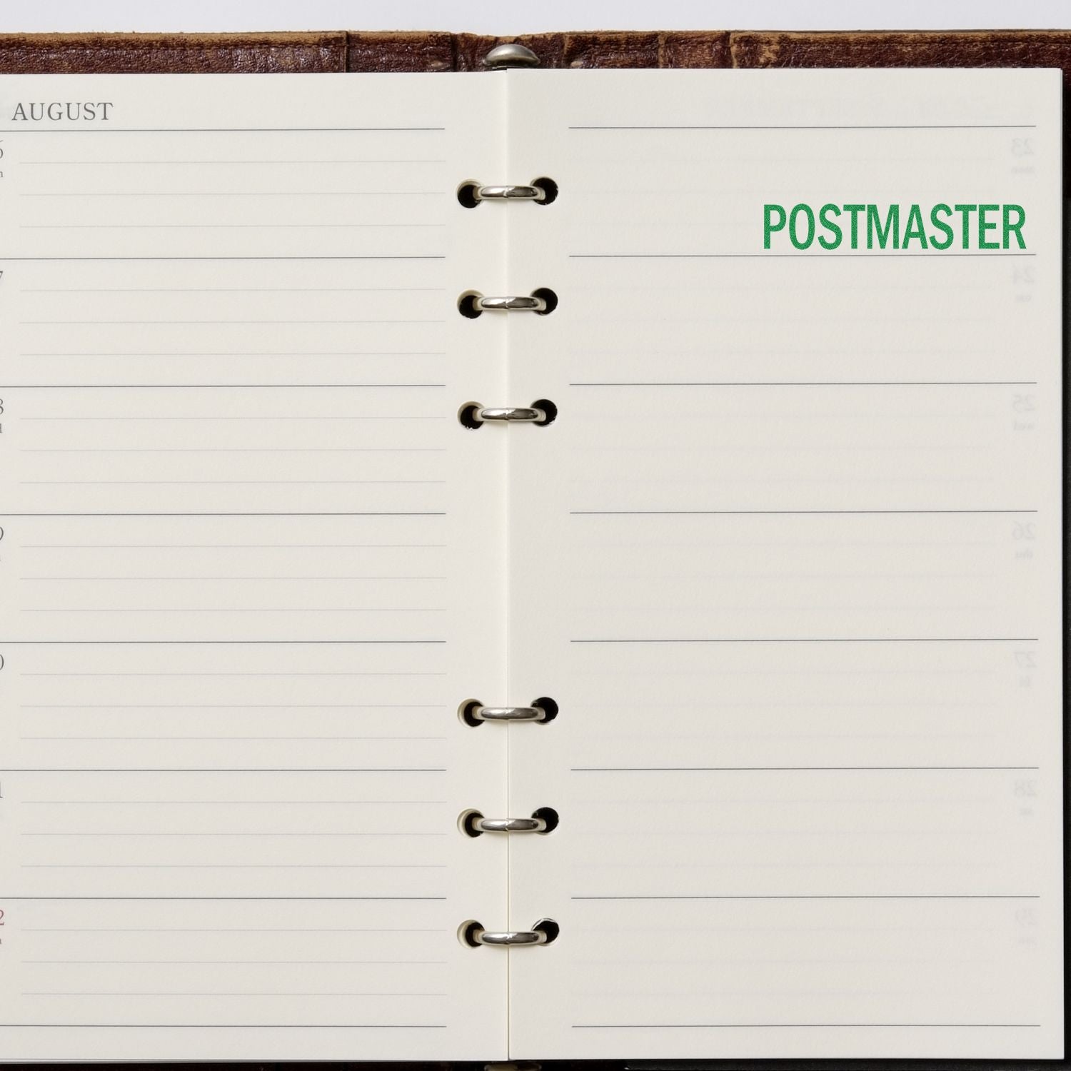 Open August planner page with binder rings and green Postmaster text, minimalist calendar layout.