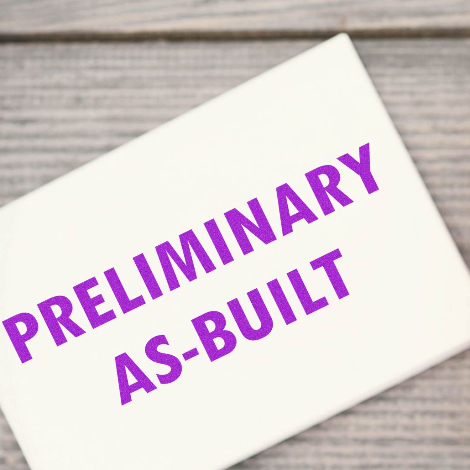 Preliminary as-built document title on a white paper card with purple text on a wooden background.