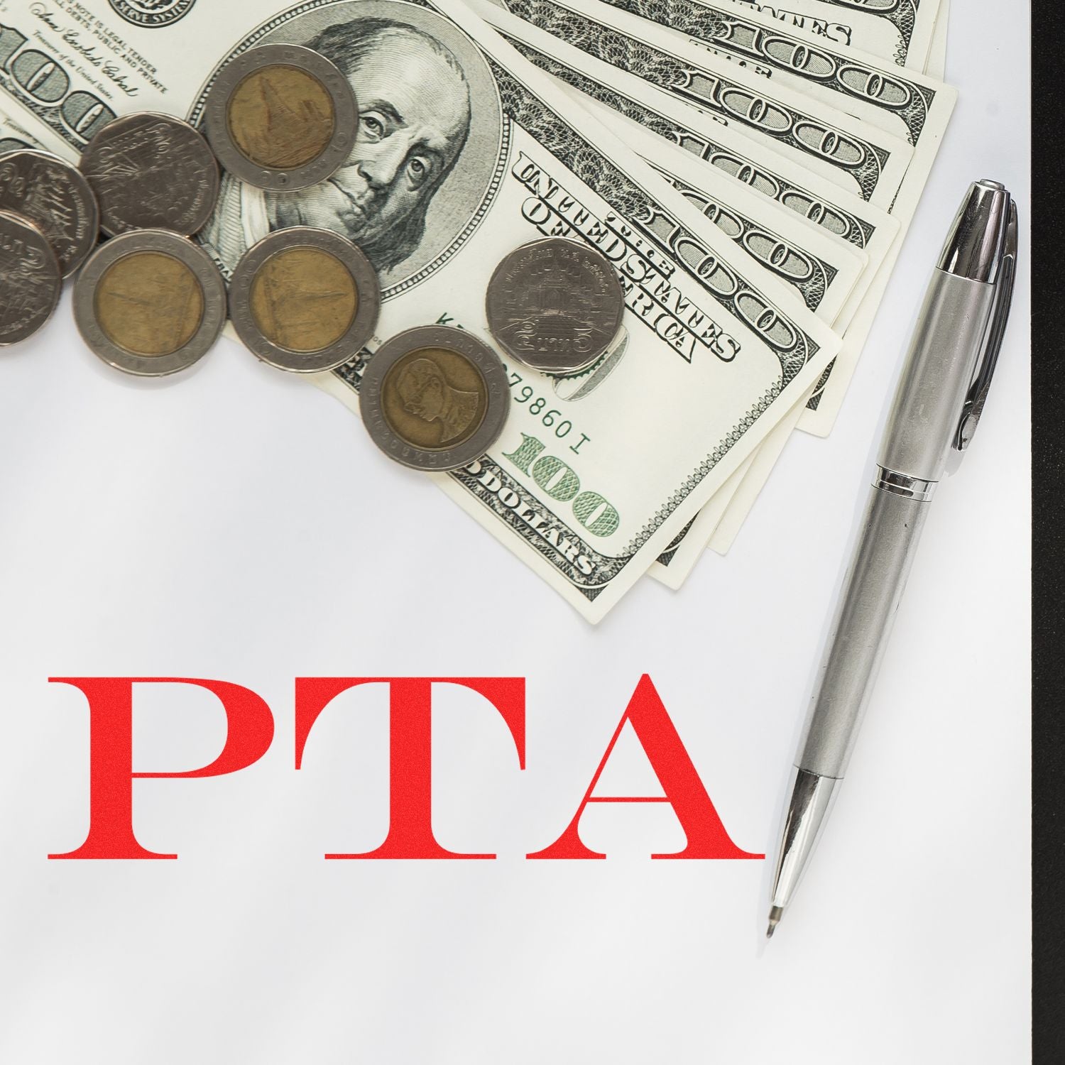 PTA fundraising budget concept with U.S. dollar bills, coins, and a silver pen on white paper
