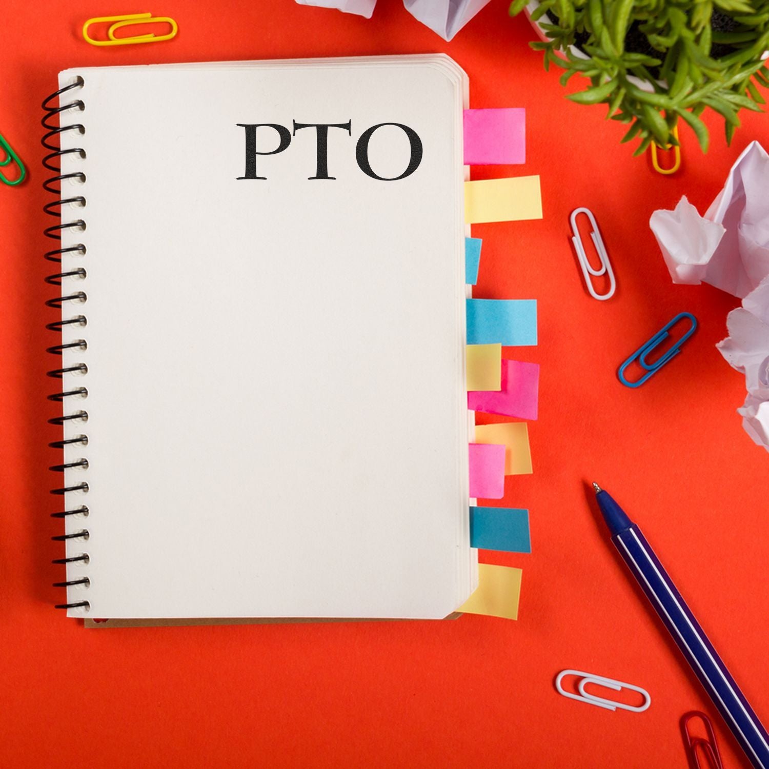 Flat lay of PTO planner on red desk with sticky notes, paper clips, and penwork leave planning reminder.