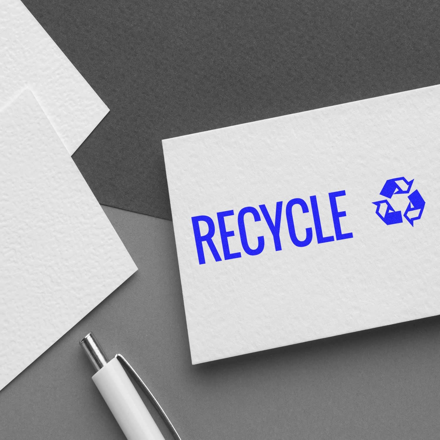 Recycle concept card with blue RECYCLE text and recycling symbol on paper, promoting sustainability and waste reduction.