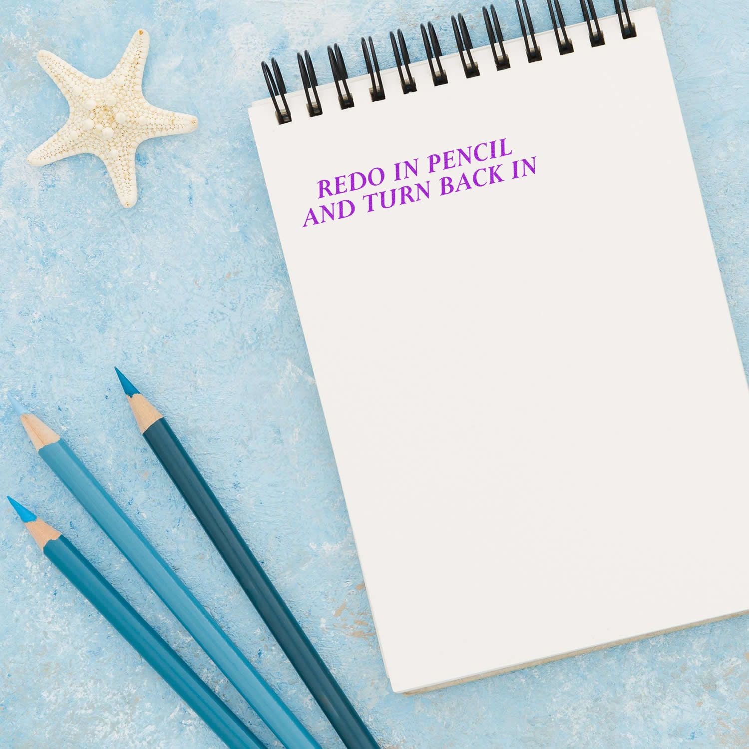Notebook with Redo in pencil and turn back in text, blue pencils, and starfish on a light blue background.