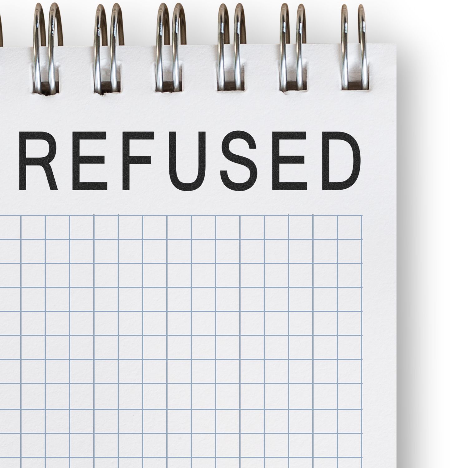 Spiral notebook with bold REFUSED text on grid paper, symbolizing rejection or denial.