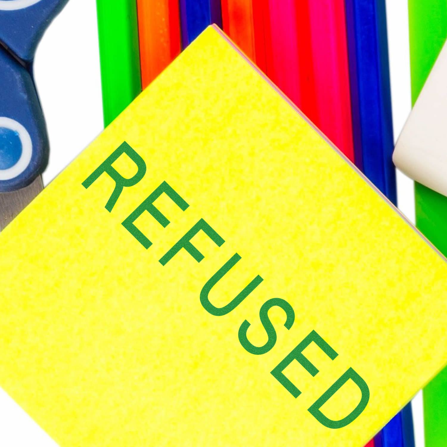 Yellow REFUSED stamp on colorful stationery background, concept of rejection or denied approval.