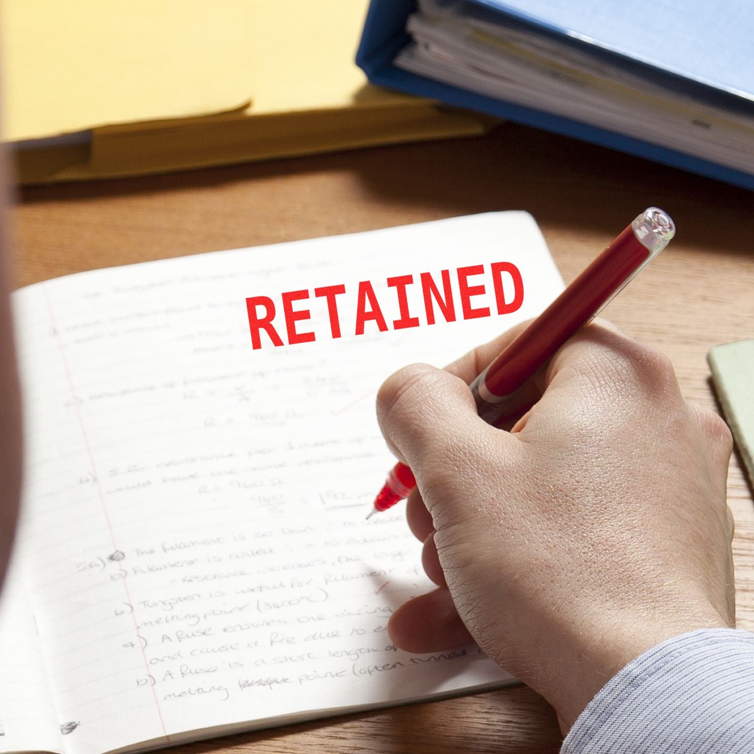 Hand holding a red pen over a document marked RETAINED, illustrating document retention and recordkeeping for audits