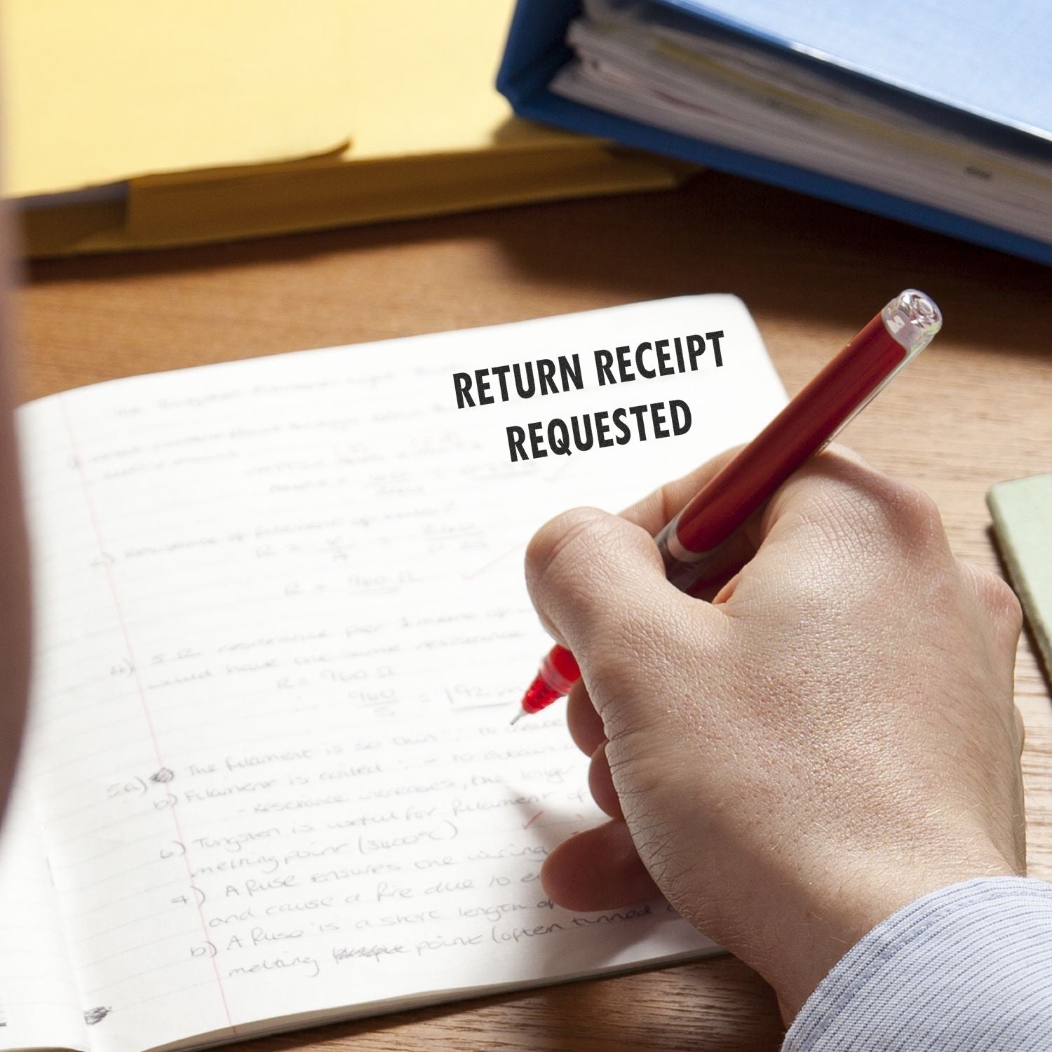 Hand writing in notebook with “return receipt requested” text, business document concept on desk.