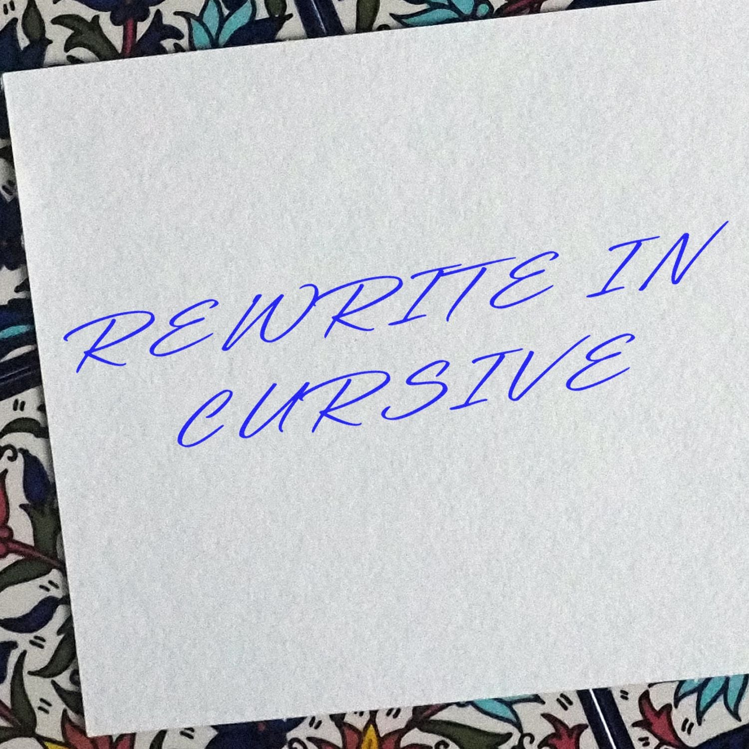 Handwritten rewrite in cursive text on white paper over a colorful patterned background.