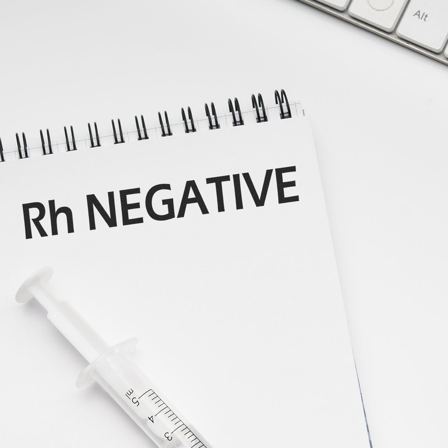Rh negative medical notebook with syringe on white desk background