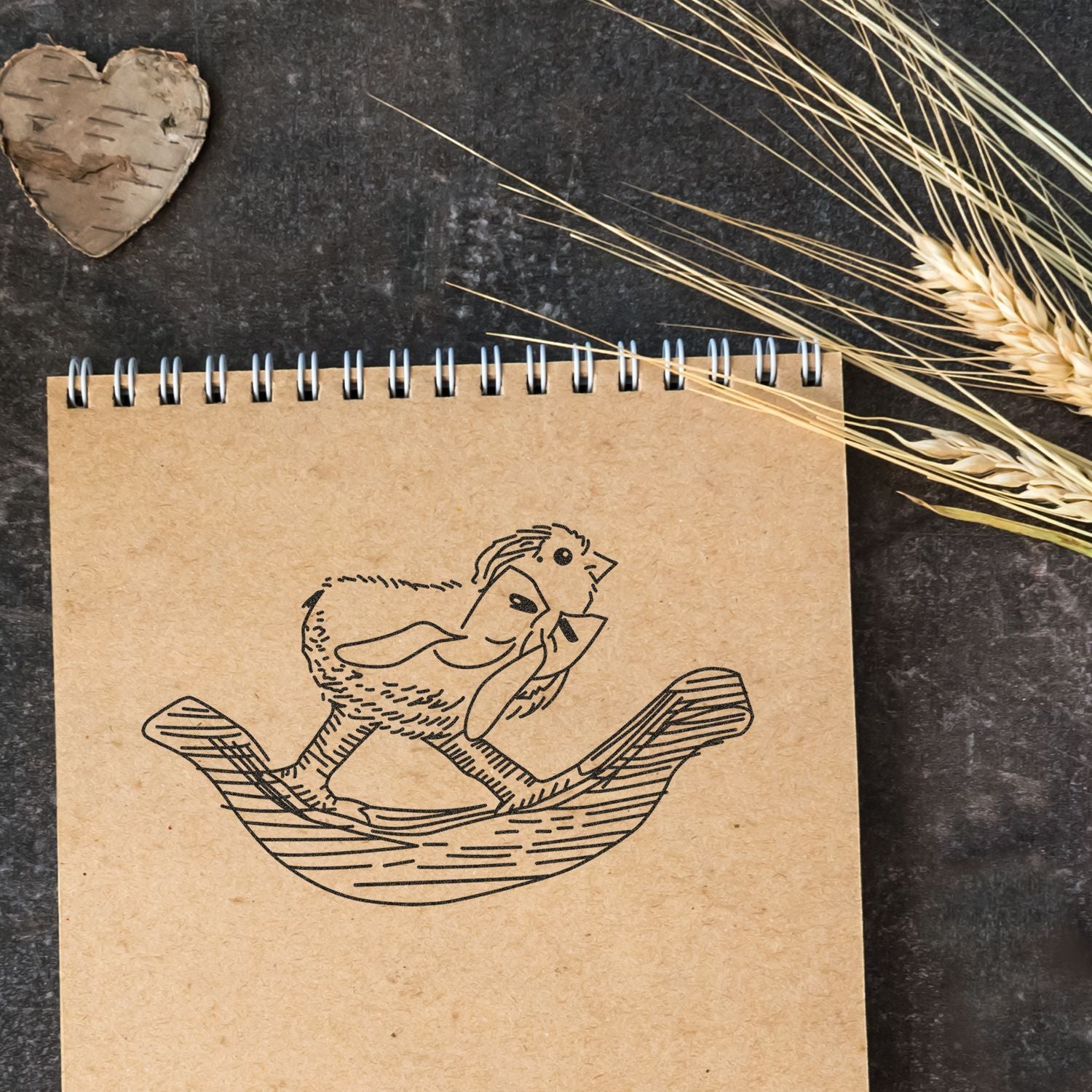 Kraft spiral notebook with cute chick illustration, rustic wheat and birch heart decor on dark background