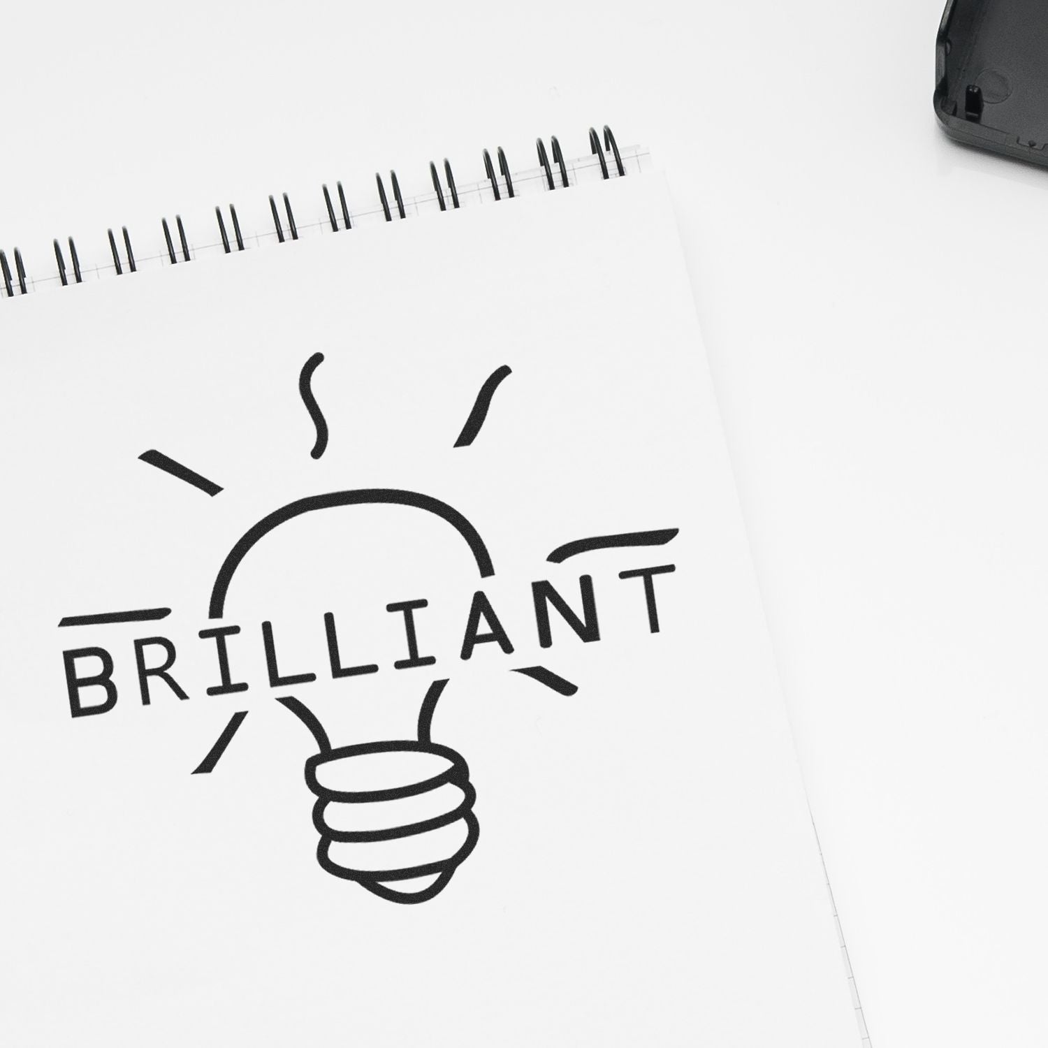 Brilliant notebook with light bulb icon on a clean white background, symbolizing creative ideas and inspiration.