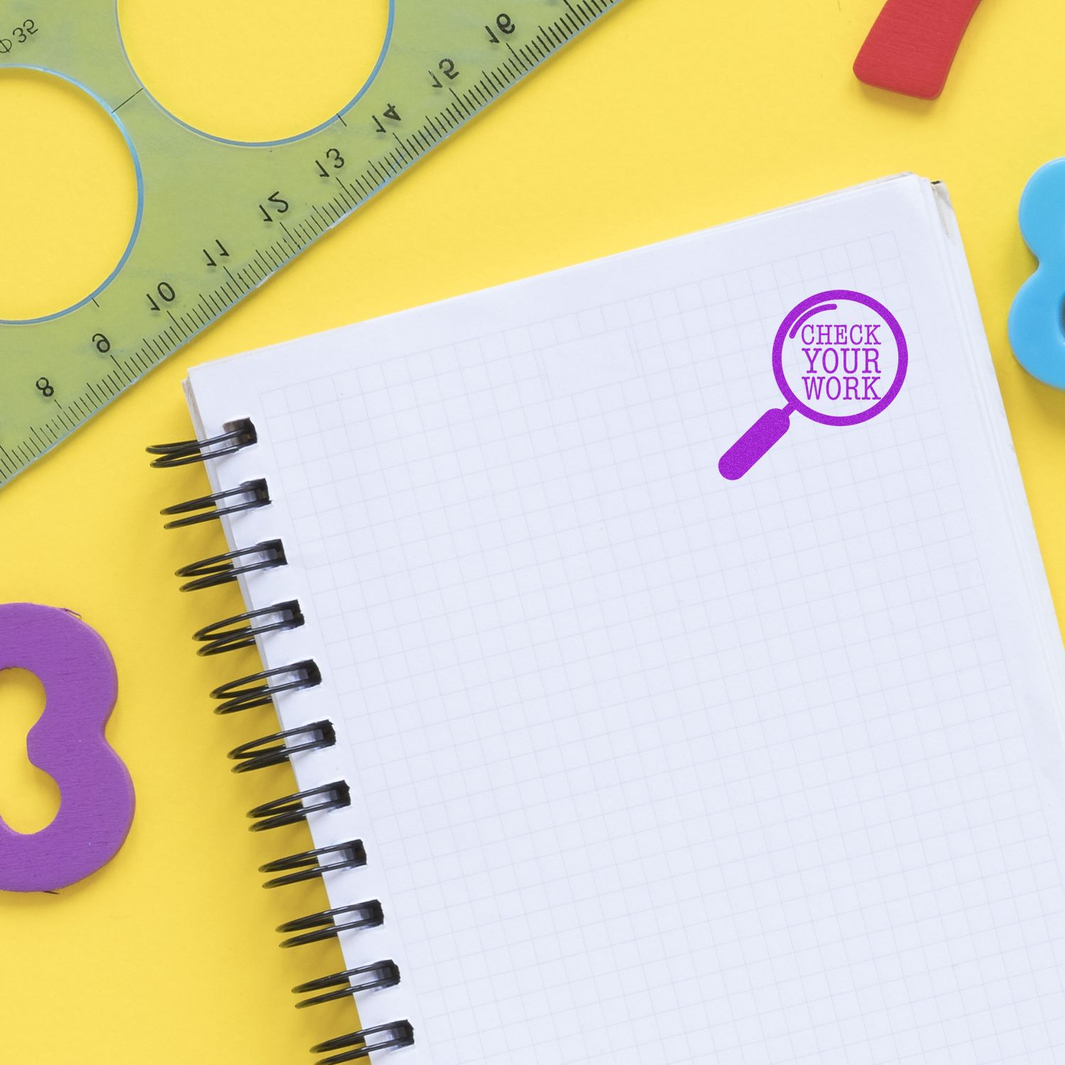 Blank spiral notebook with check your work magnifying glass, ruler, and colorful school supplies on a yellow background.