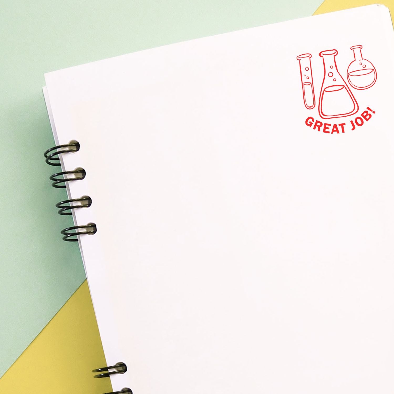 Blank spiral notebook page with Great Job! science lab flask stamp on pastel background