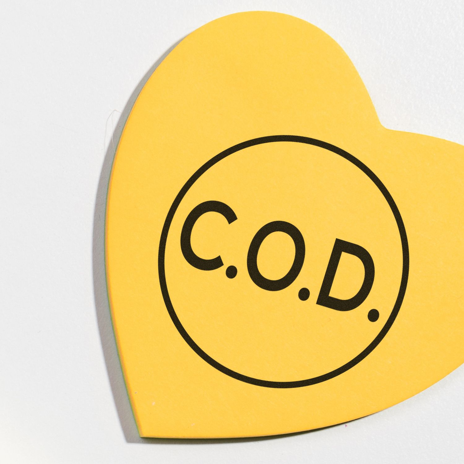 Yellow heart-shaped C.O.D. sign with black text on a white background