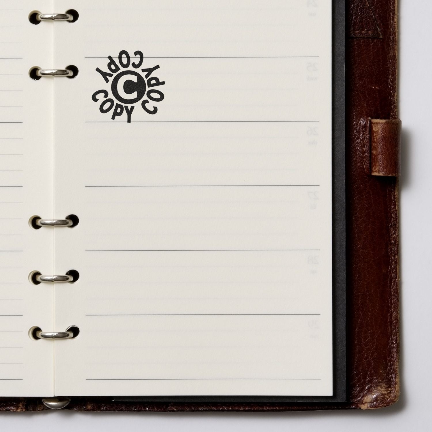 Close-up of an open leather ring planner with lined pages and a copyright copy symbol.