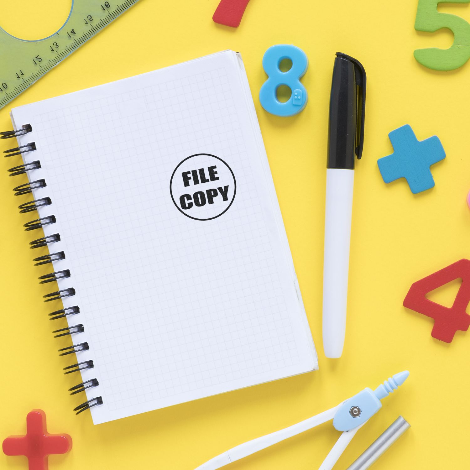 Notebook with File Copy stamp, pen, and colorful back to school stationery on a yellow background