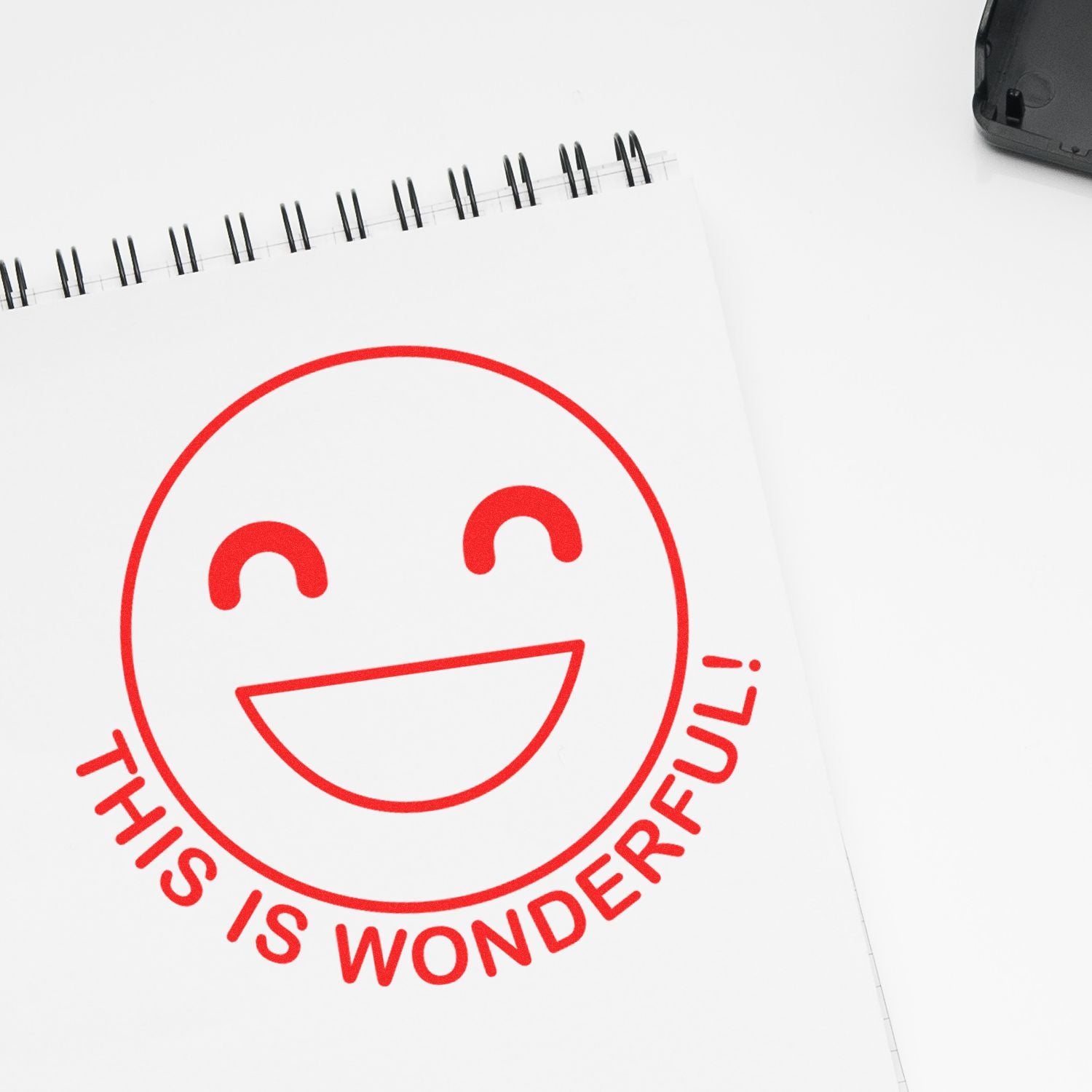 Notebook with red smiley face and This Is Wonderful! text on a white background.