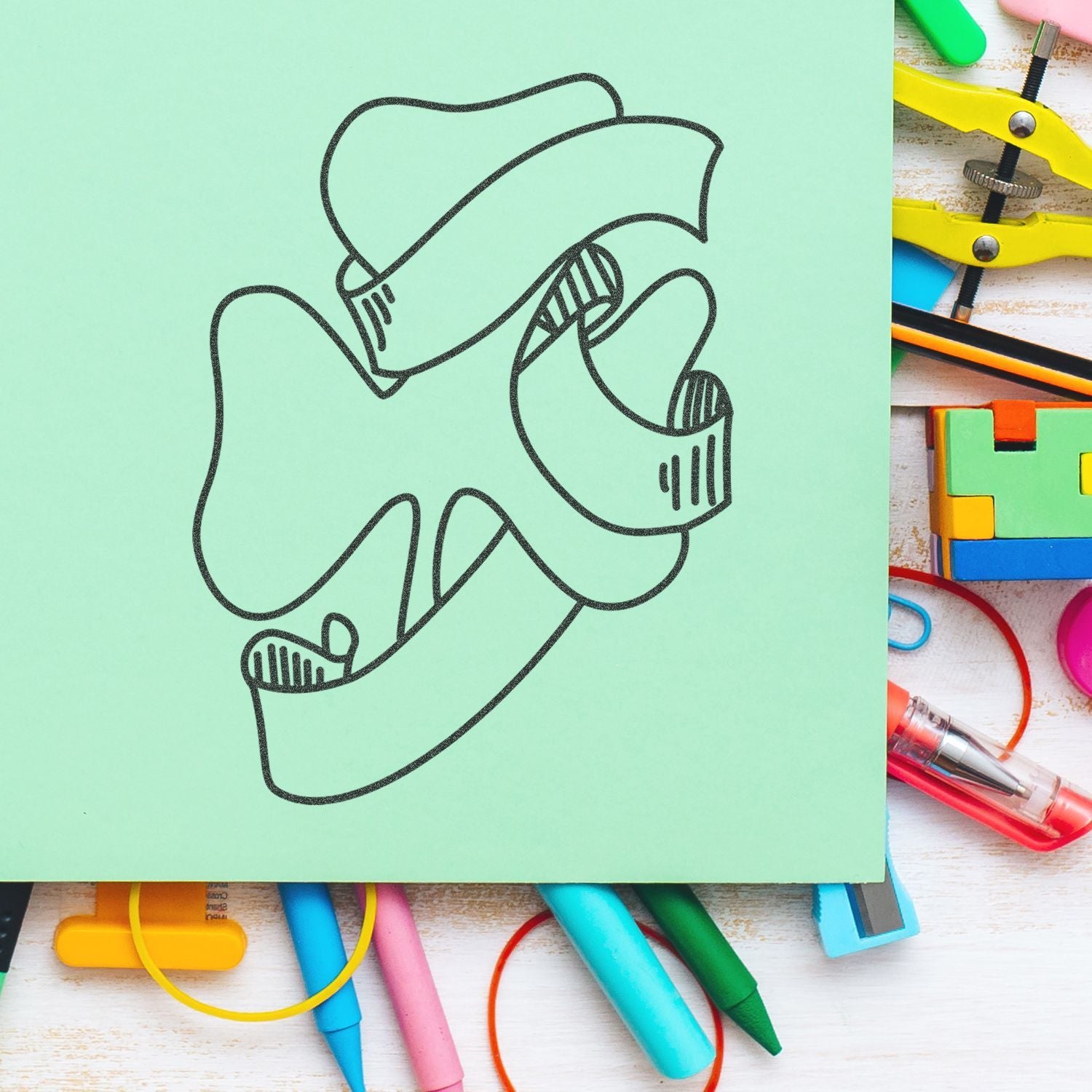 Abstract black line art doodle on pastel green paper surrounded by colorful school supplies and stationery accessories.