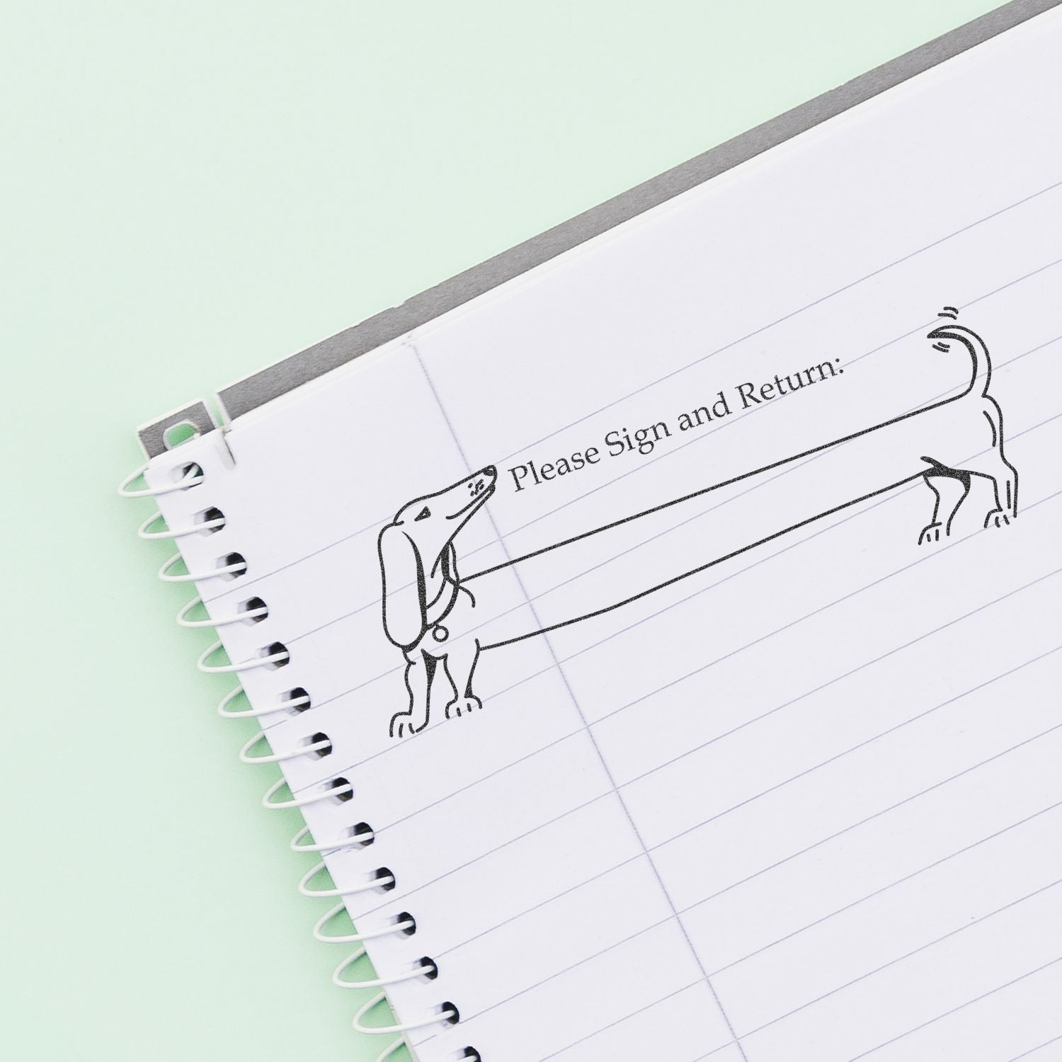 Notebook page with Please Sign and Return text and playful dog illustration on lined paper.