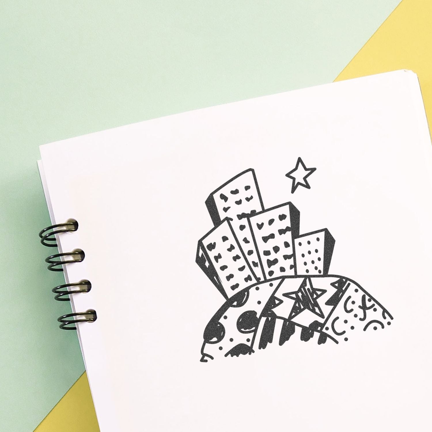 Spiral notebook with abstract black doodle city skyline illustration on pastel background, creative sketchbook cover design.