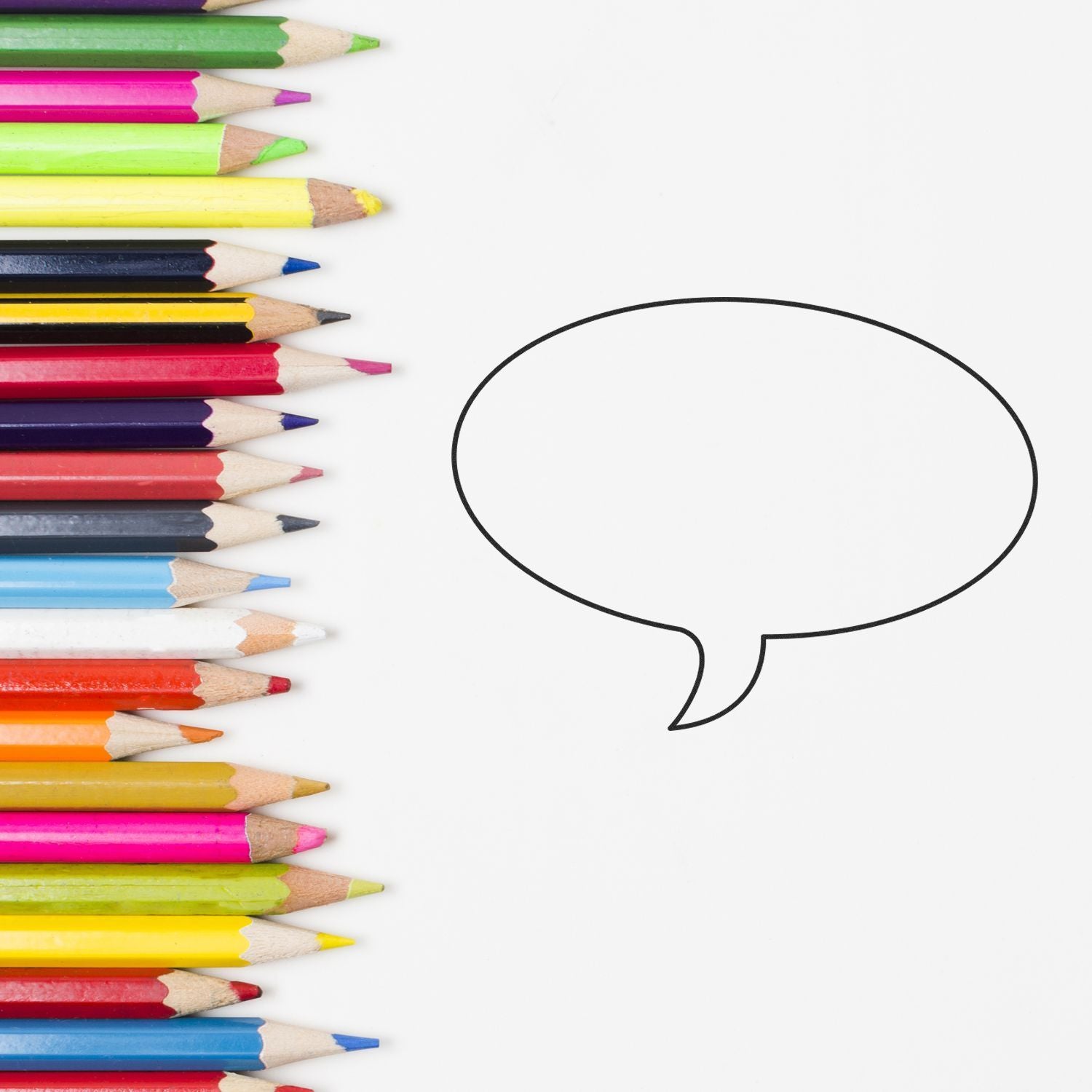 Colorful colored pencils lined up beside a blank speech bubble on a white background, creative education concept.
