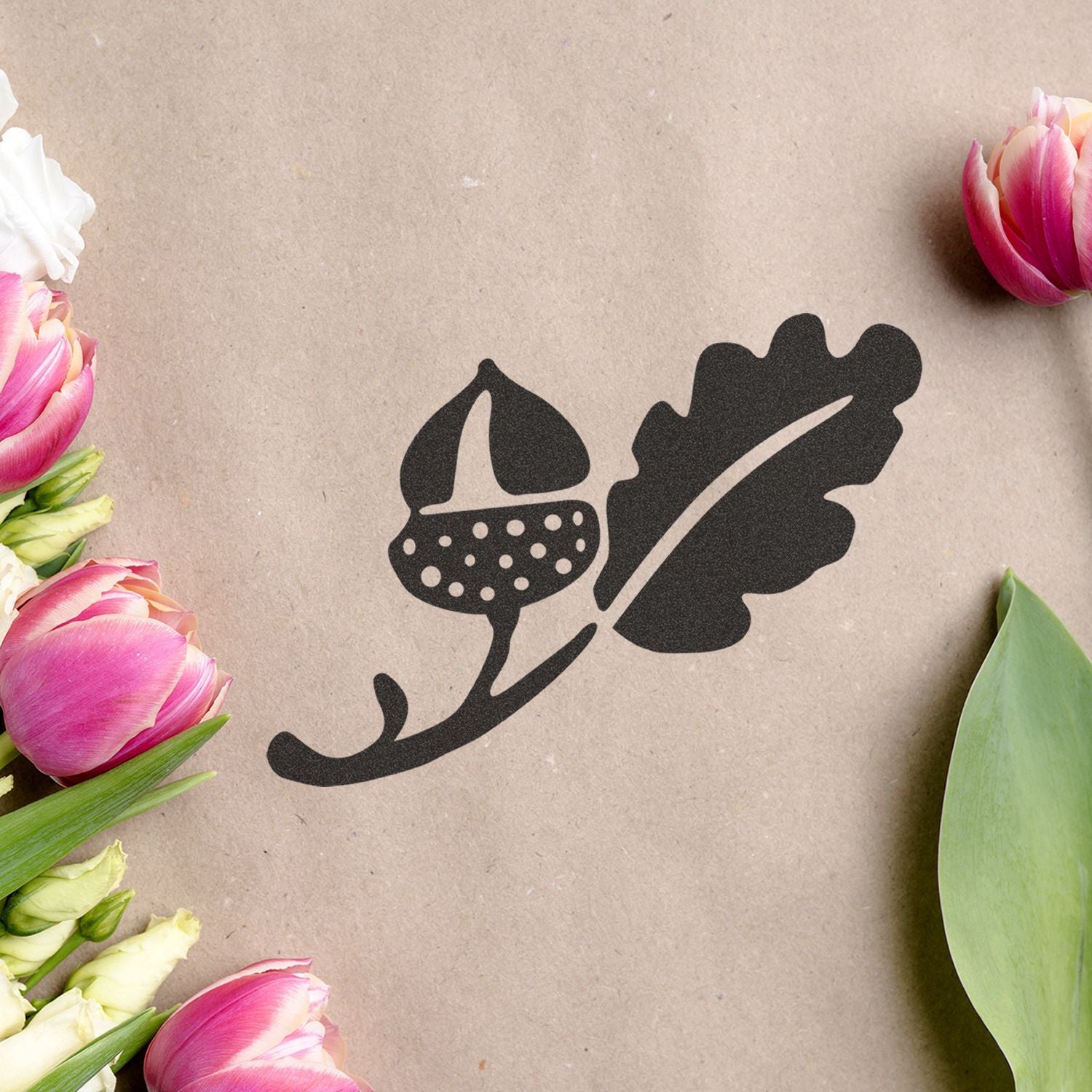 Black acorn and oak leaf floral logo on kraft paper with pink tulips border, rustic botanical design background