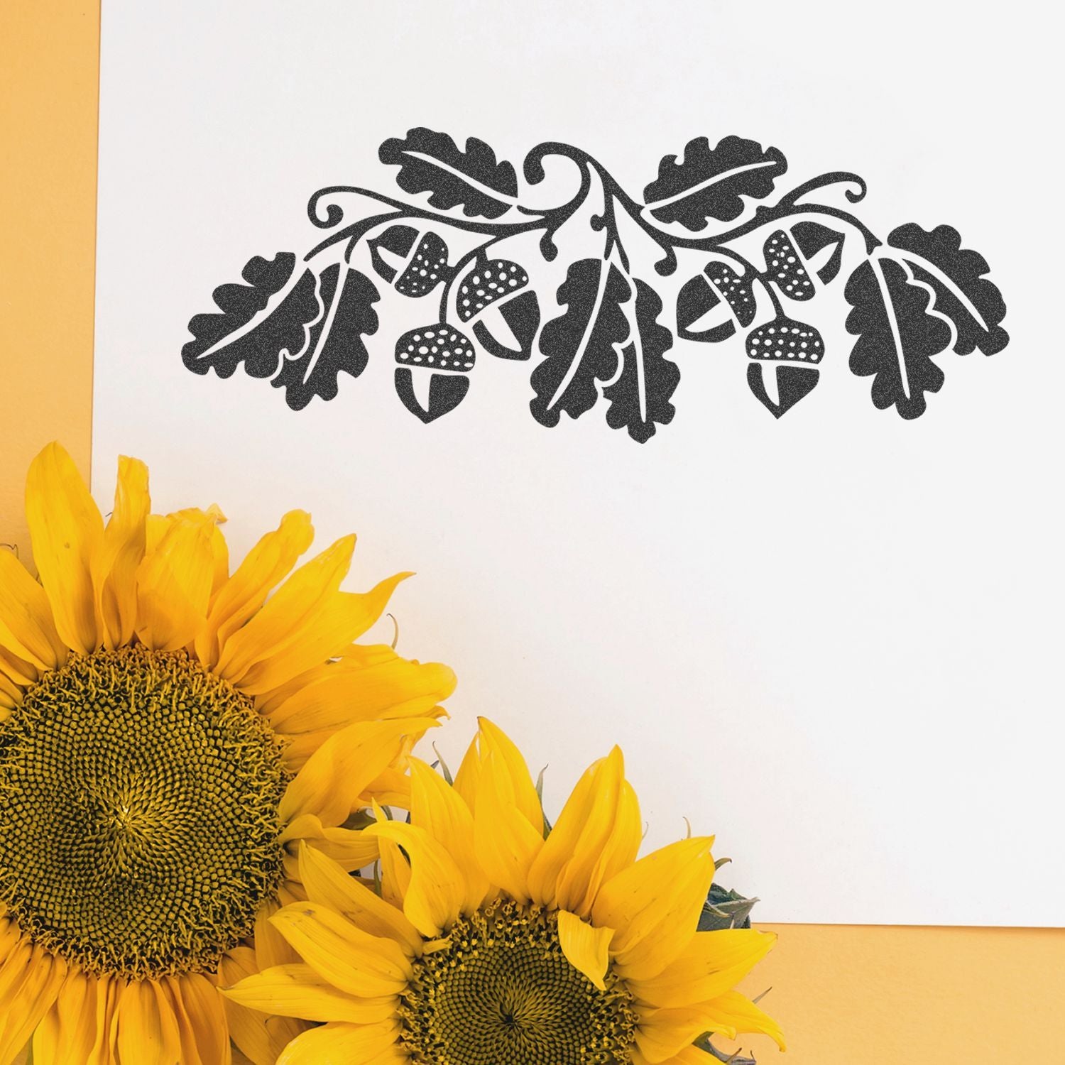 Black oak leaf and acorn wall art with bright sunflowers on a white and yellow background.