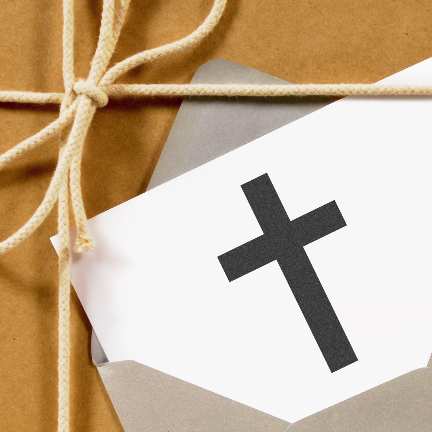 Gift wrapped in brown kraft paper with twine and a white card featuring a black cross symbol.