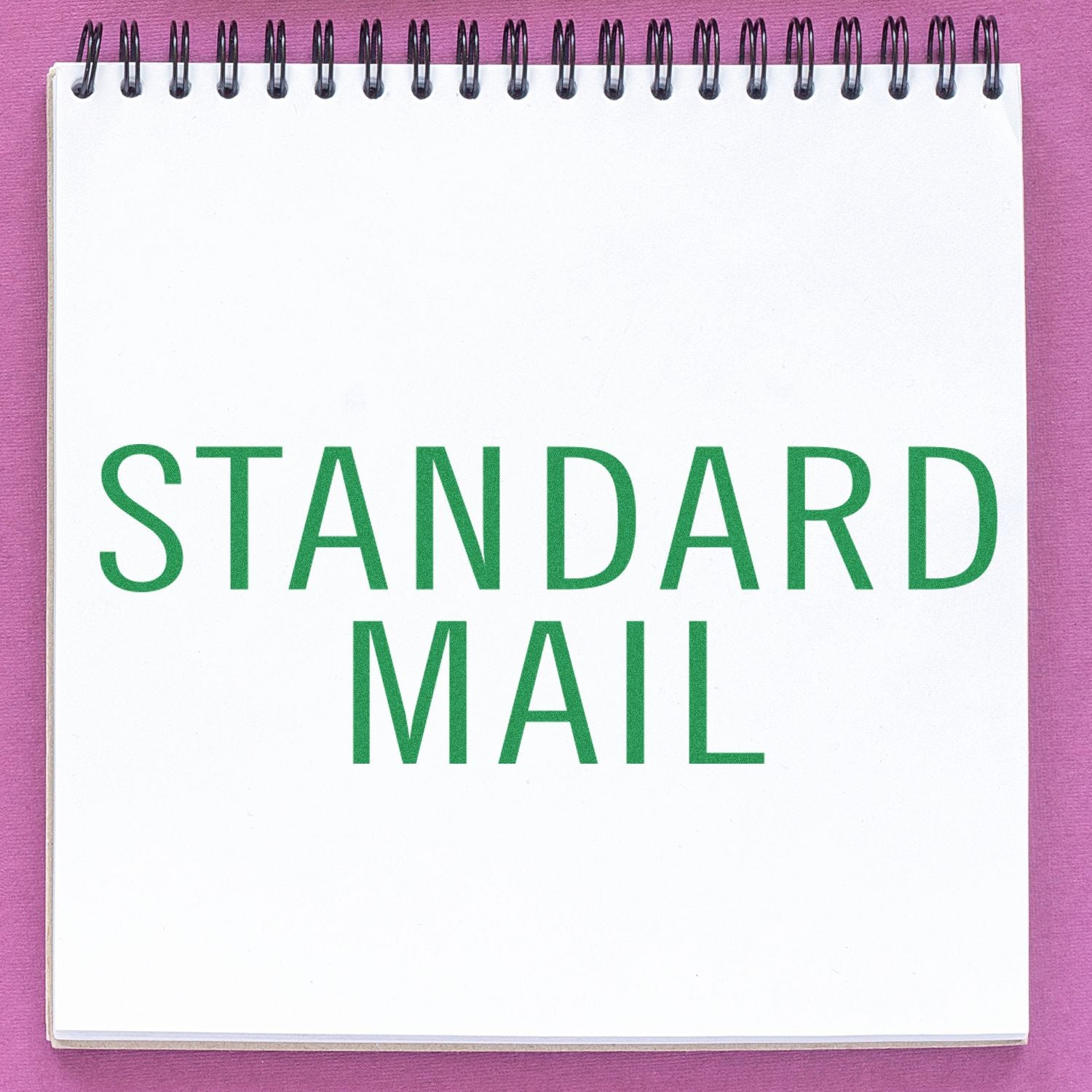Notebook with STANDARD MAIL text on a pink background, ideal for postal or office communication concept.
