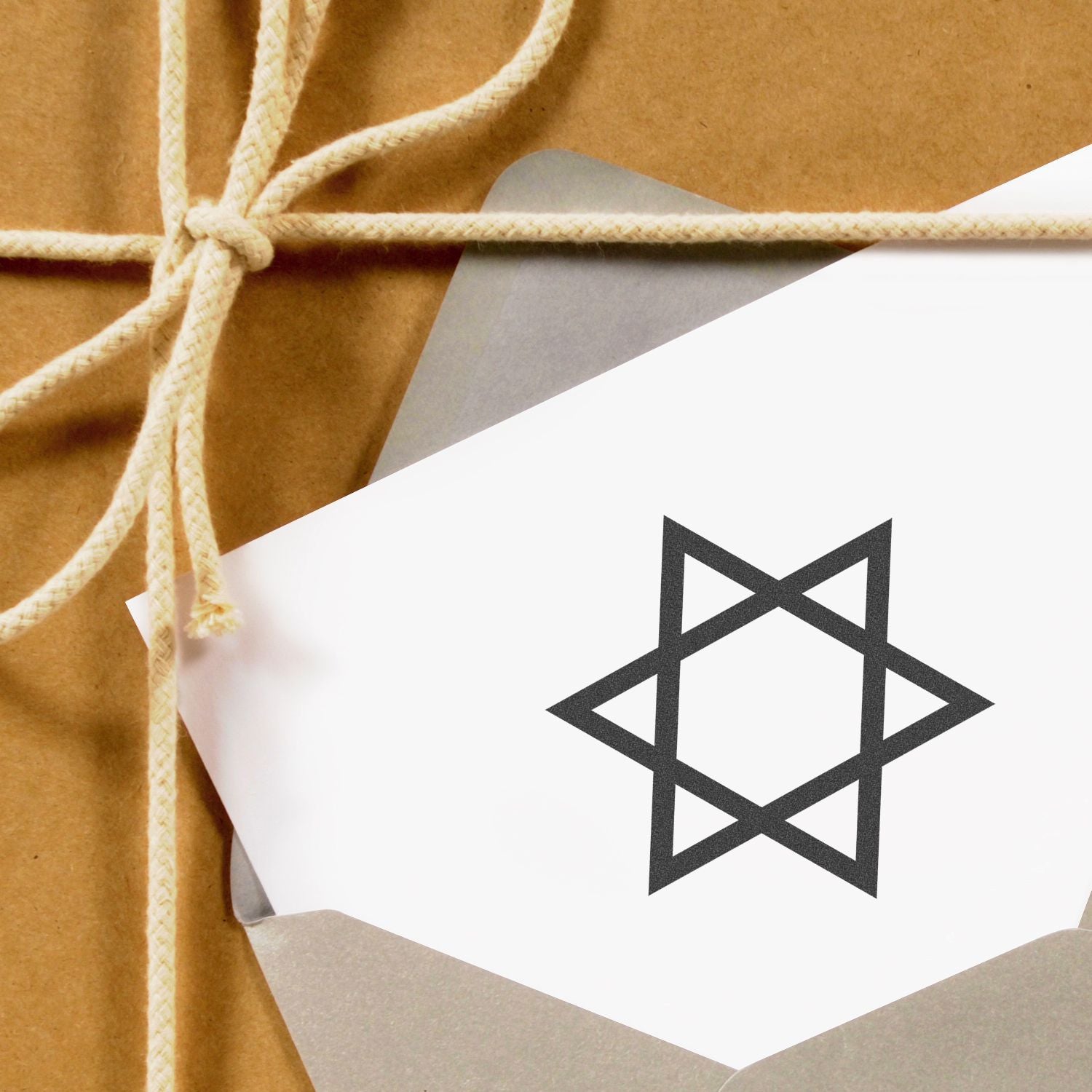 Close-up of a kraft paper wrapped gift tied with twine and a white label featuring a geometric star logo.