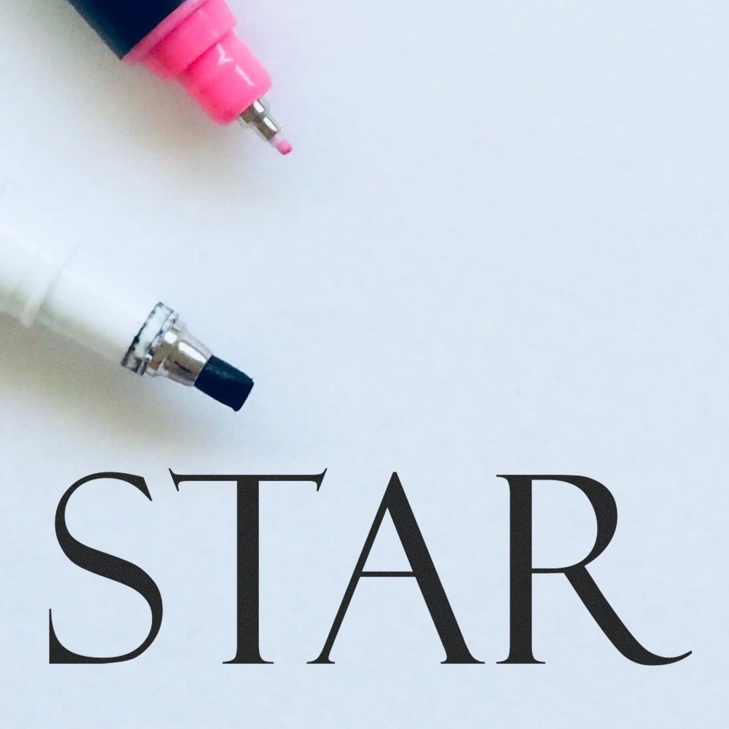 Close-up of pink and black pen tips above the word STAR on a white background.