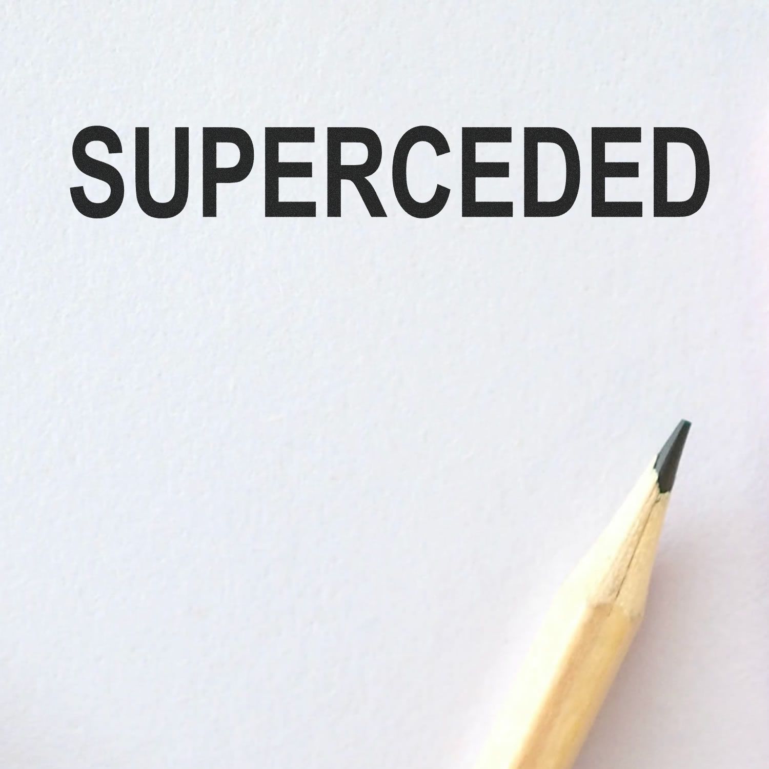 Pencil beside the word SUPERCEDED on white paper.