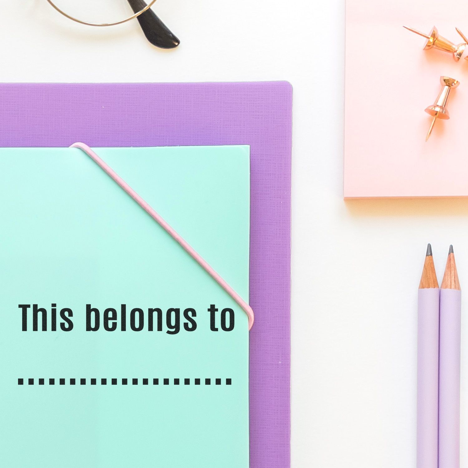 Flat lay stationery with This belongs to label, showing notebooks, pencils, and pins for organizing personal items.