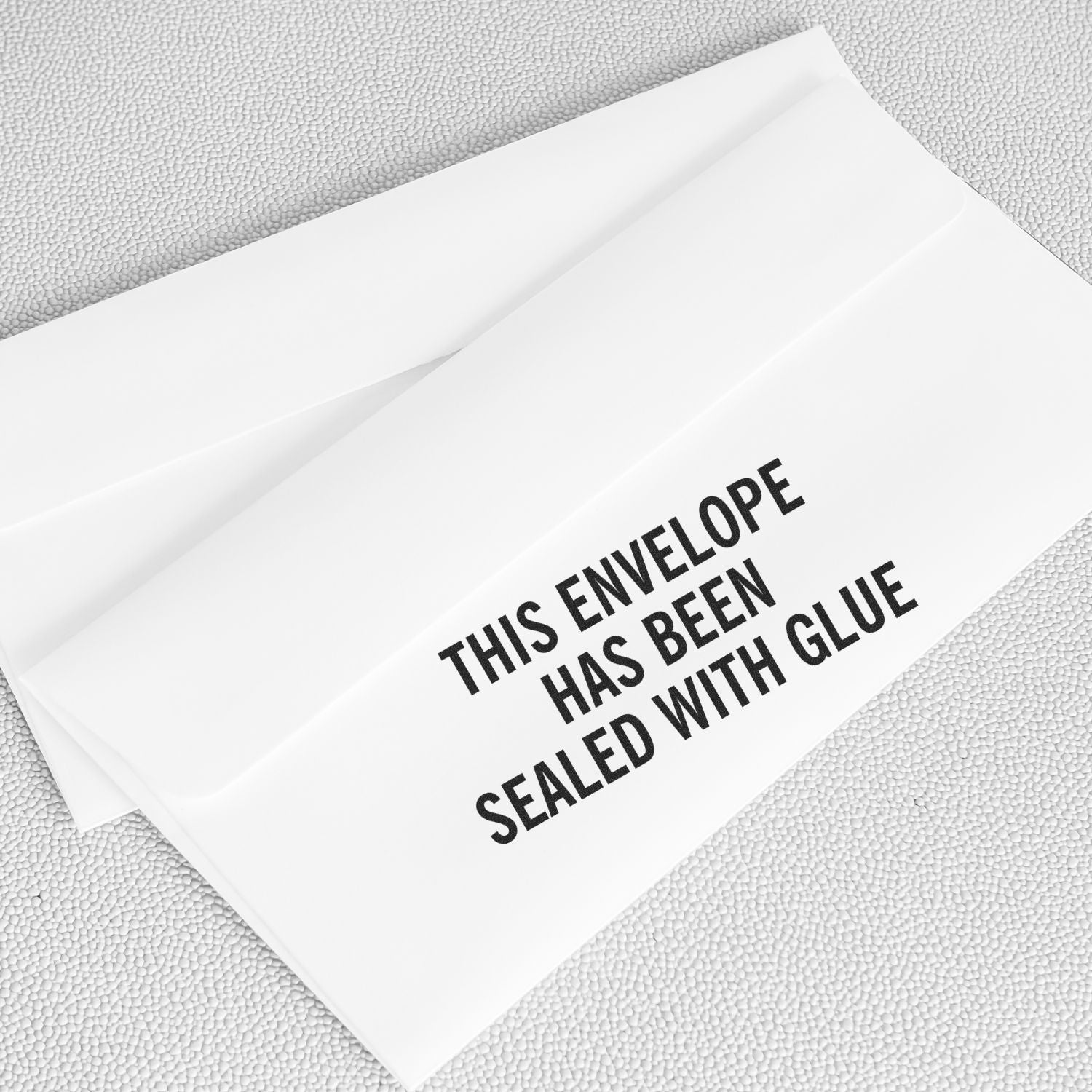 White envelope on textured background with text This envelope has been sealed with glue for secure sealing proof, tamper-evident delivery