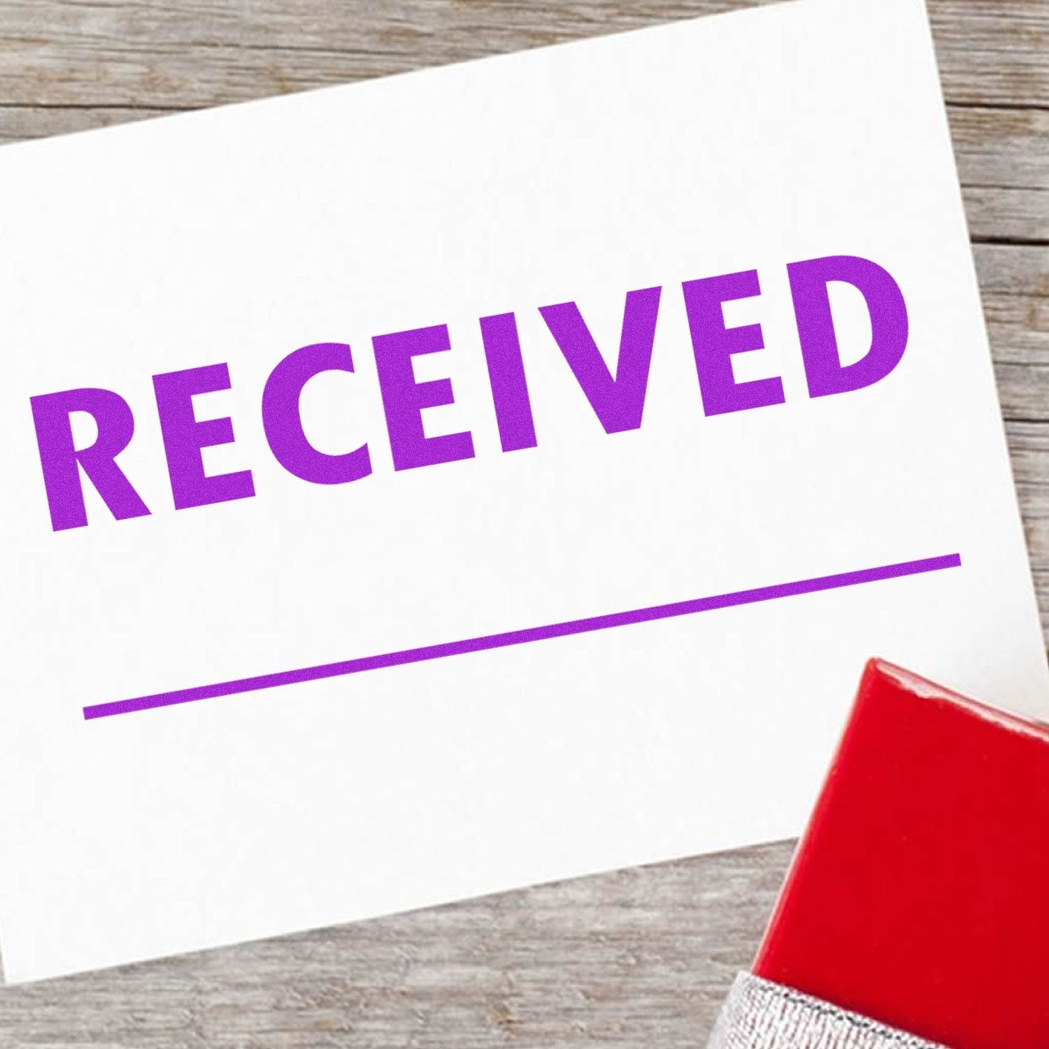 RECEIVED stamp on a document with red envelope corner on rustic wooden desk, indicating package or paperwork receipt.