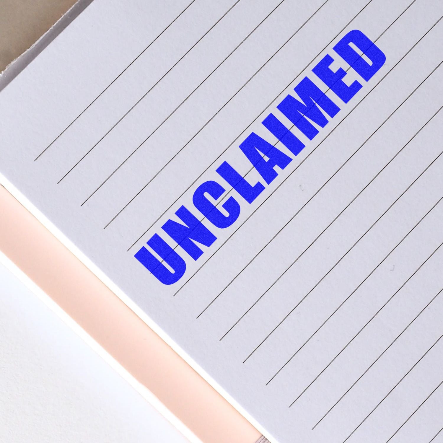 Blue UNCLAIMED stamp on lined notebook paper, close-up of a blank document page.