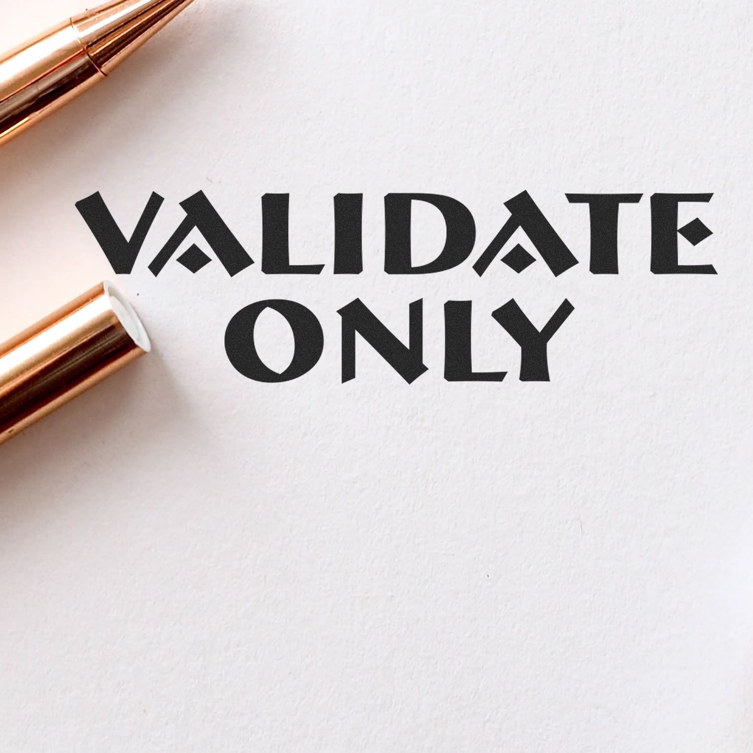 Close-up of VALIDATE ONLY text on white paper with rose gold pen, minimalist business concept illustration.