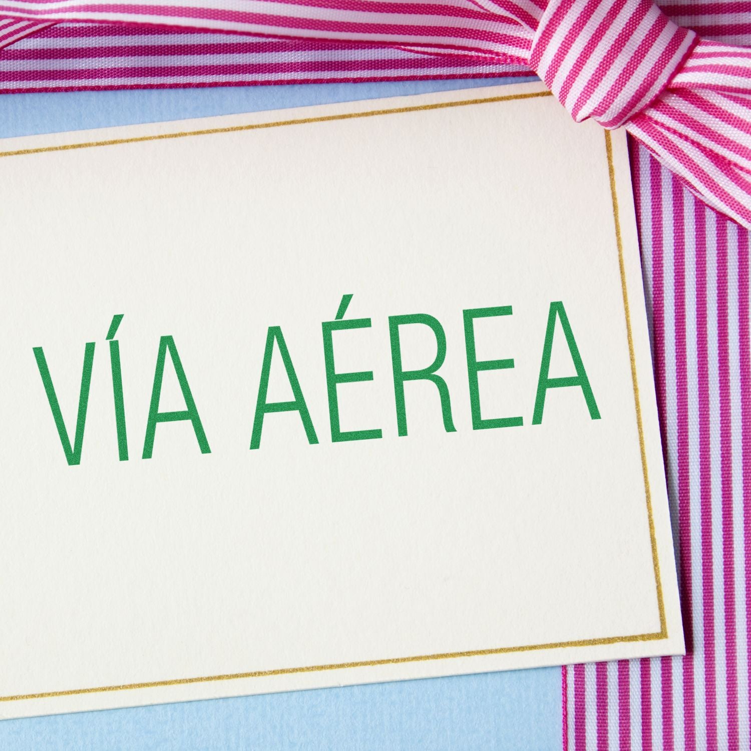 VI AREA shipping label on a greeting card with pink and white striped ribbon, highlighting air freight delivery for travelers.